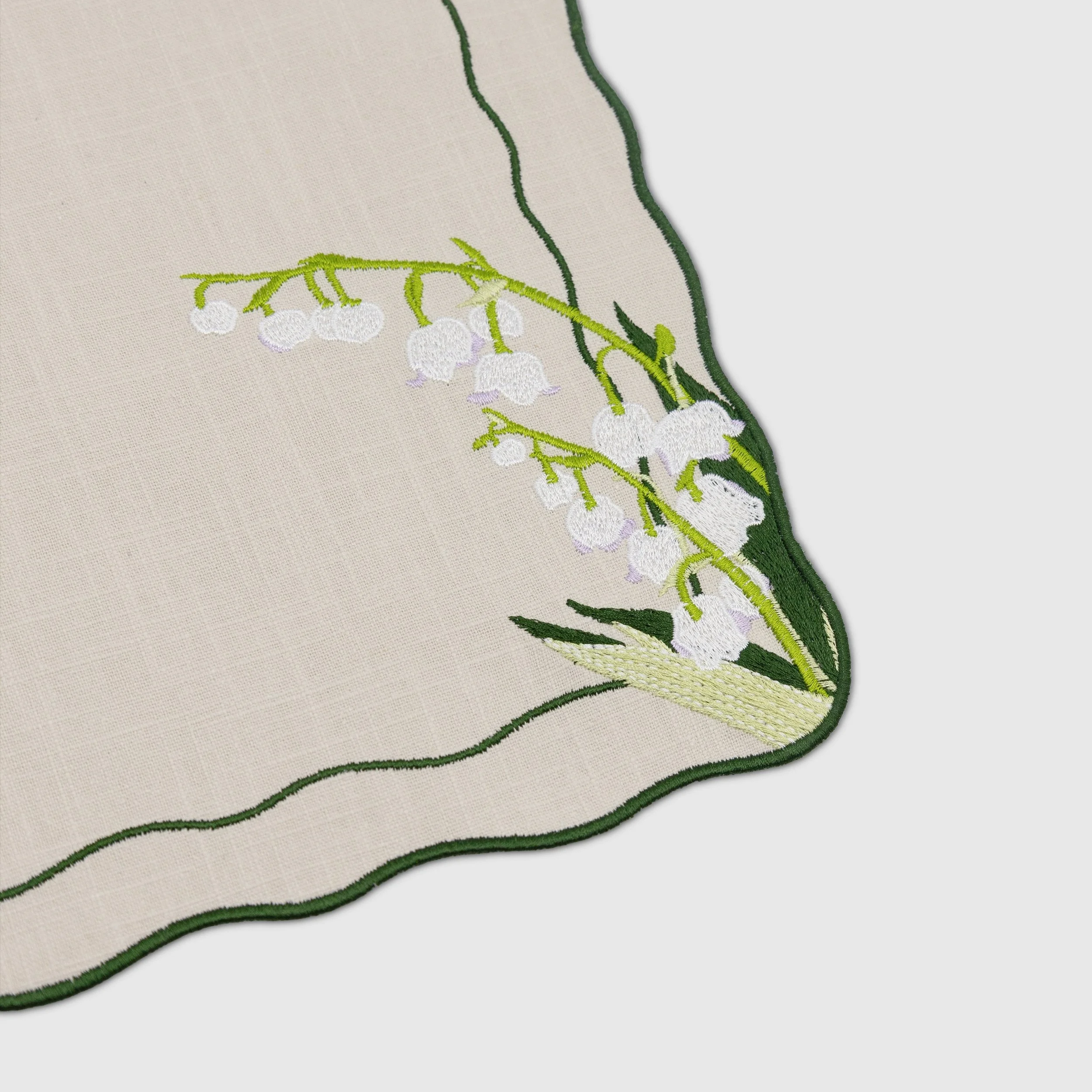 Close-up detail of lily of the valley embroidery and scalloped embroidered edge on the placemat