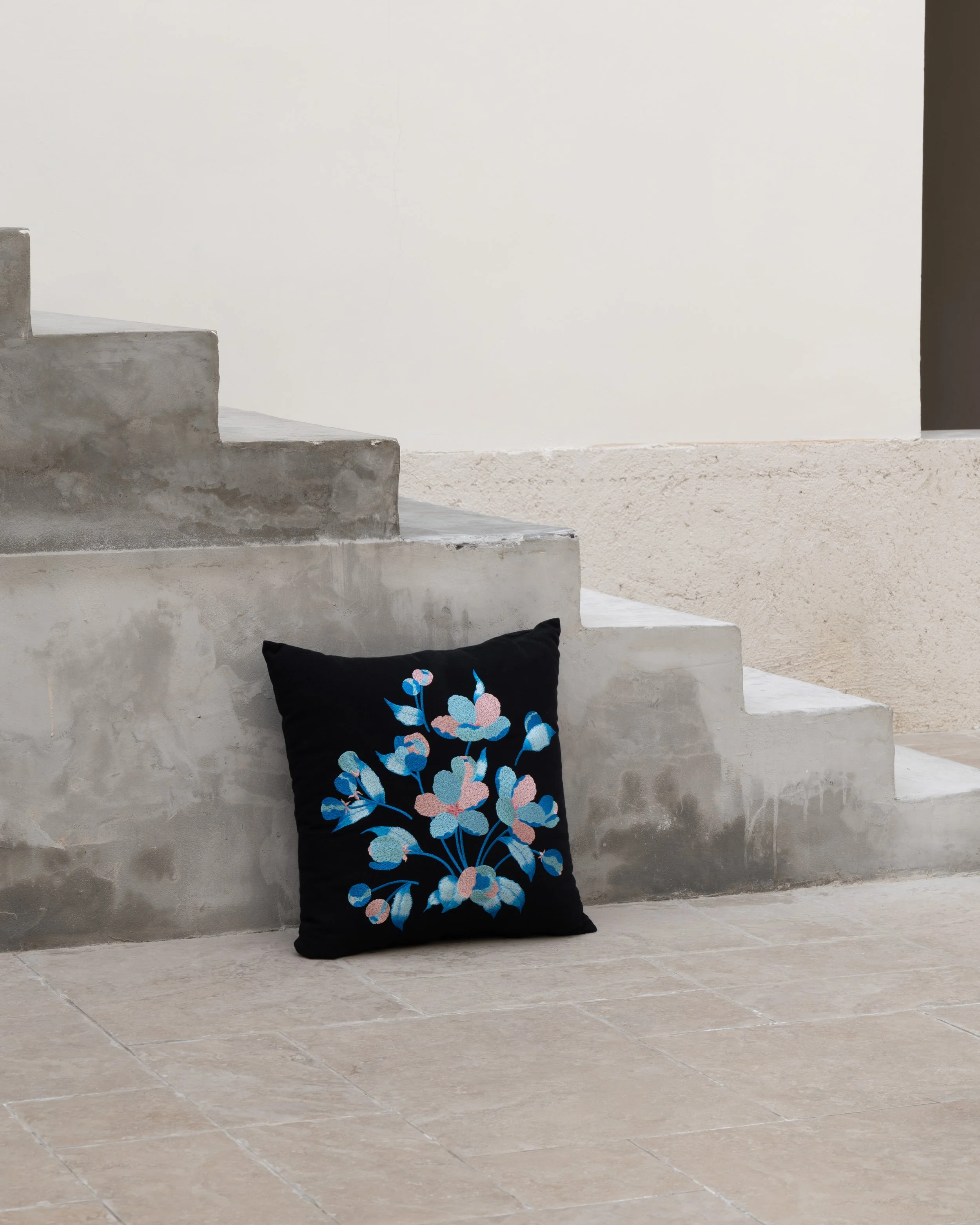 Embroidered throw pillow from the Etherelle series placed against the concrete steps.jpg