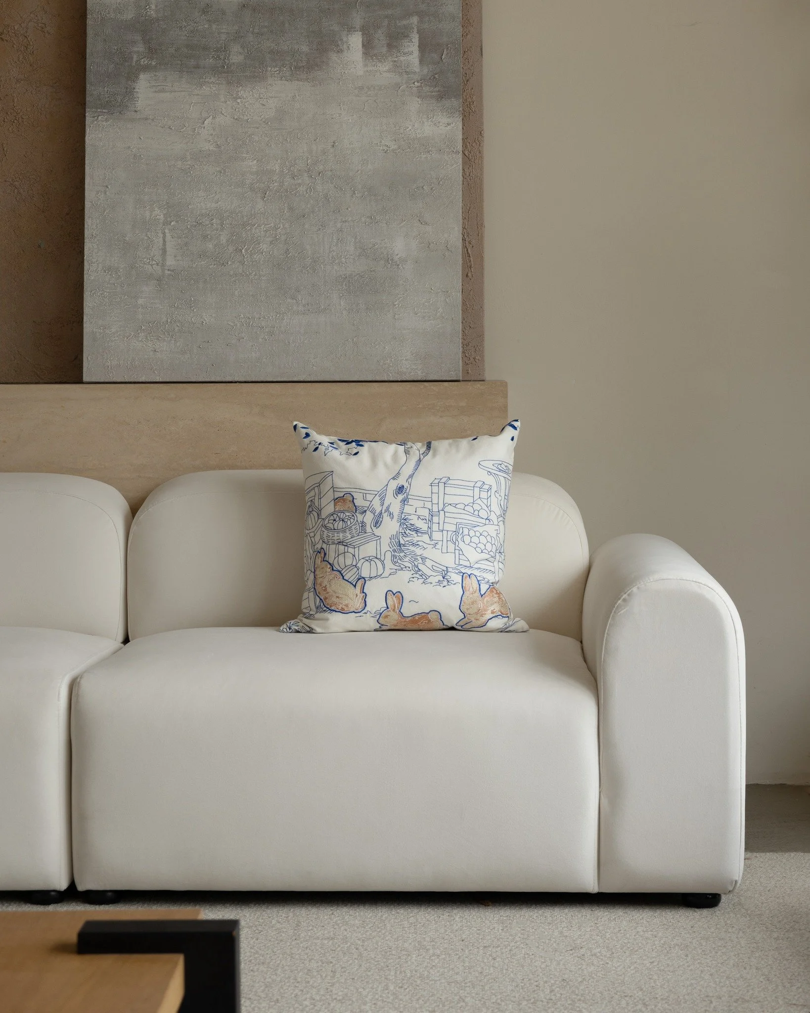 Whimsy series embroidered throw pillow with blue pastoral illustration and rabbits, styled on a soft cream sofa near a window with natural light.

#embroideredpillows #embroideredcushion #throwpillows #decorativepillow #modernhomedecor #sofadecor #pa