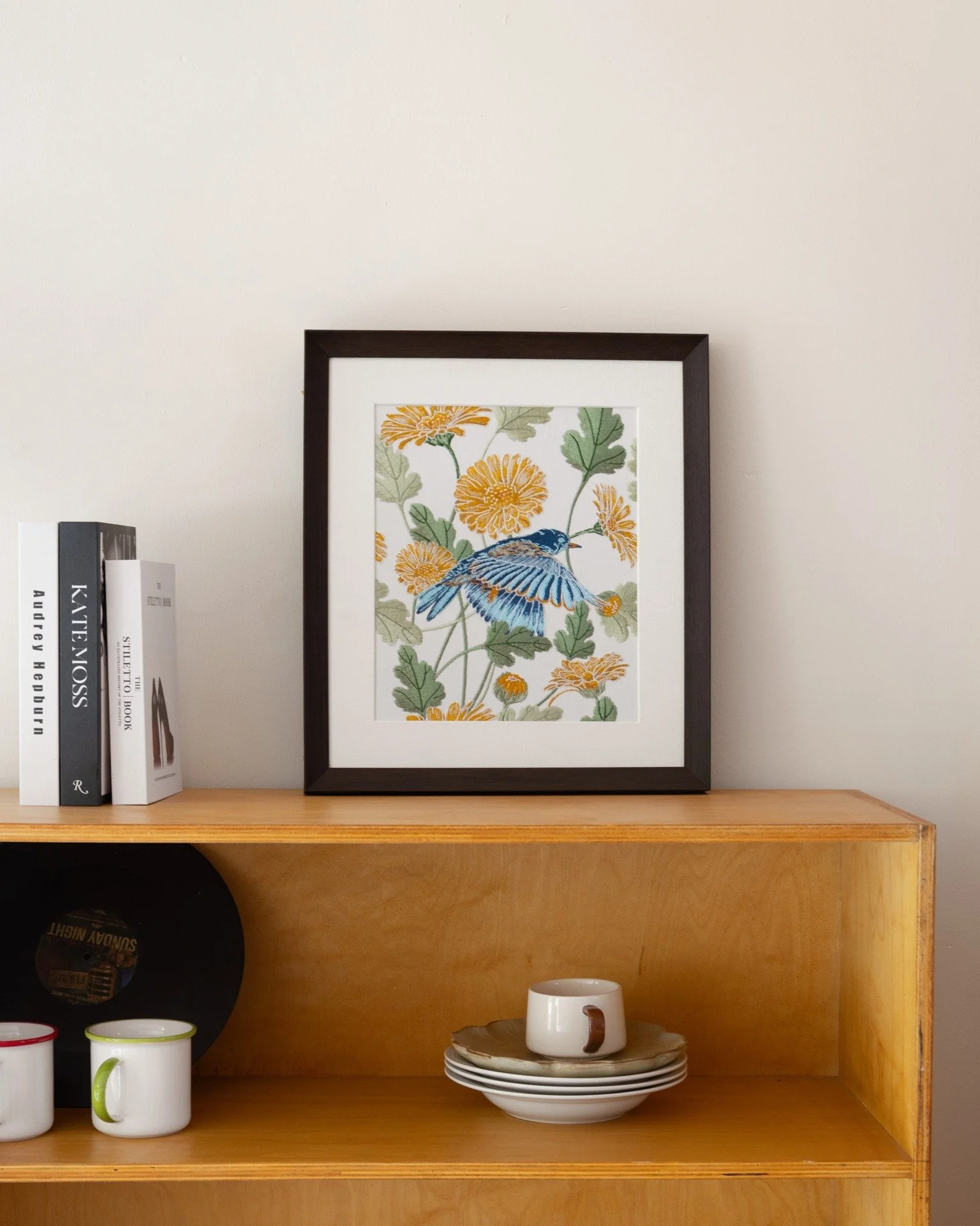 If you&rsquo;re drawn to a quieter kind of color in your space, this nature-inspired embroidery piece brings just enough movement without overwhelming it. The bluebird sits lightly among calendula blooms, adding a gentle sense of life against the war