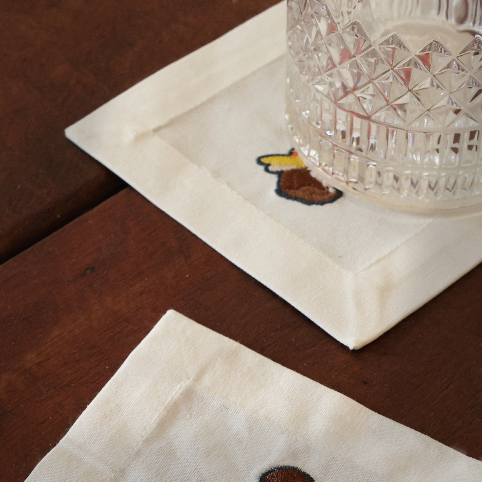 Cocktail napkins with a whisky glass placed on a dark brown wooden table