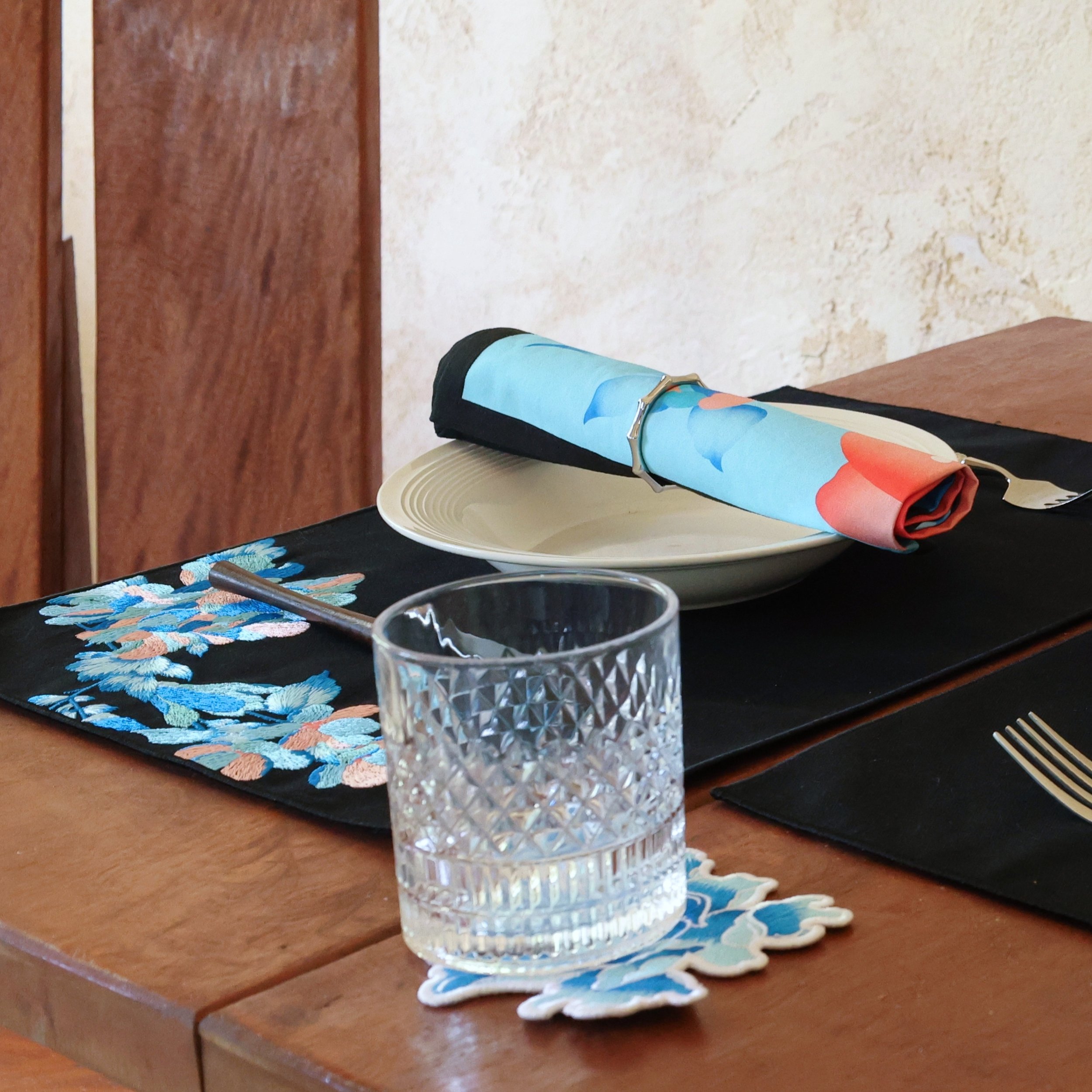 Etherelle series embroidered blue flower coaster in table setting with matching placemats and napkins