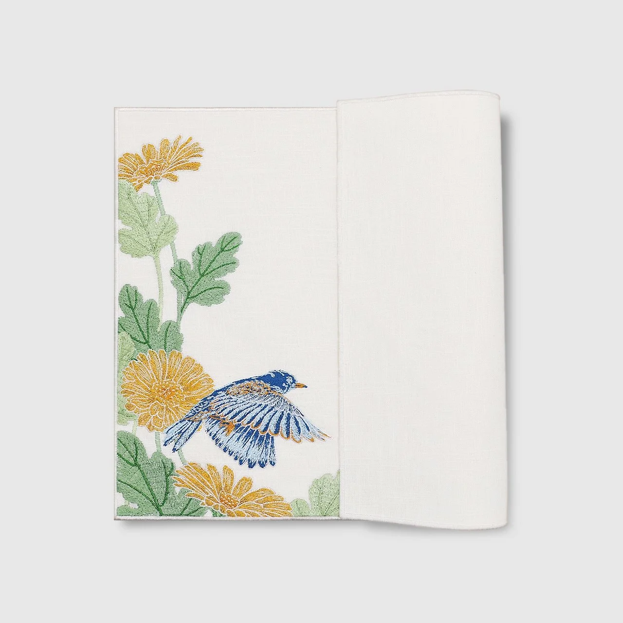 Backside details of embroidered placemat from the Garden series with a blue bird and golden calendulas