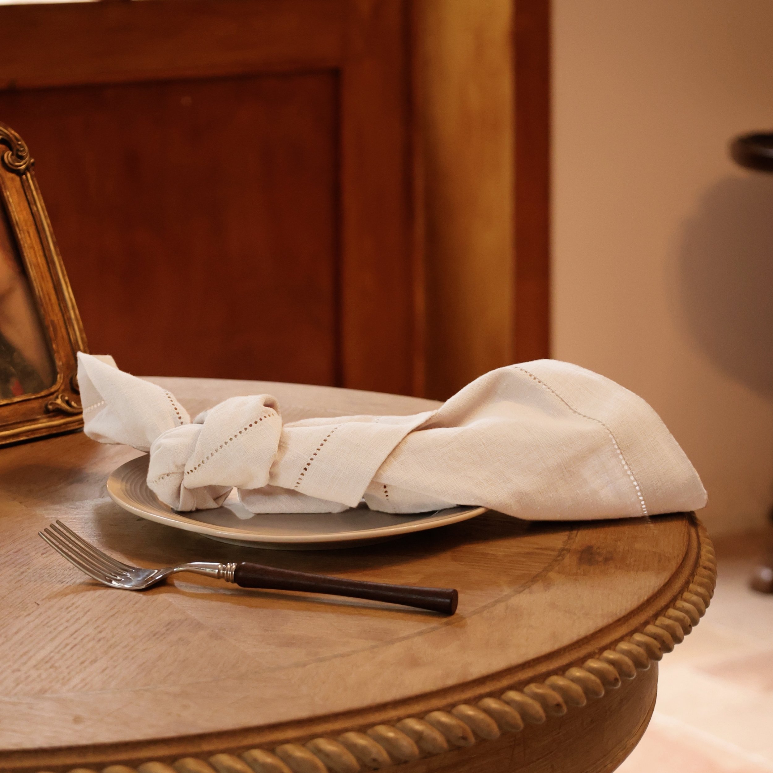 French white hemstitched cotton ramie napkin tied on a small round table