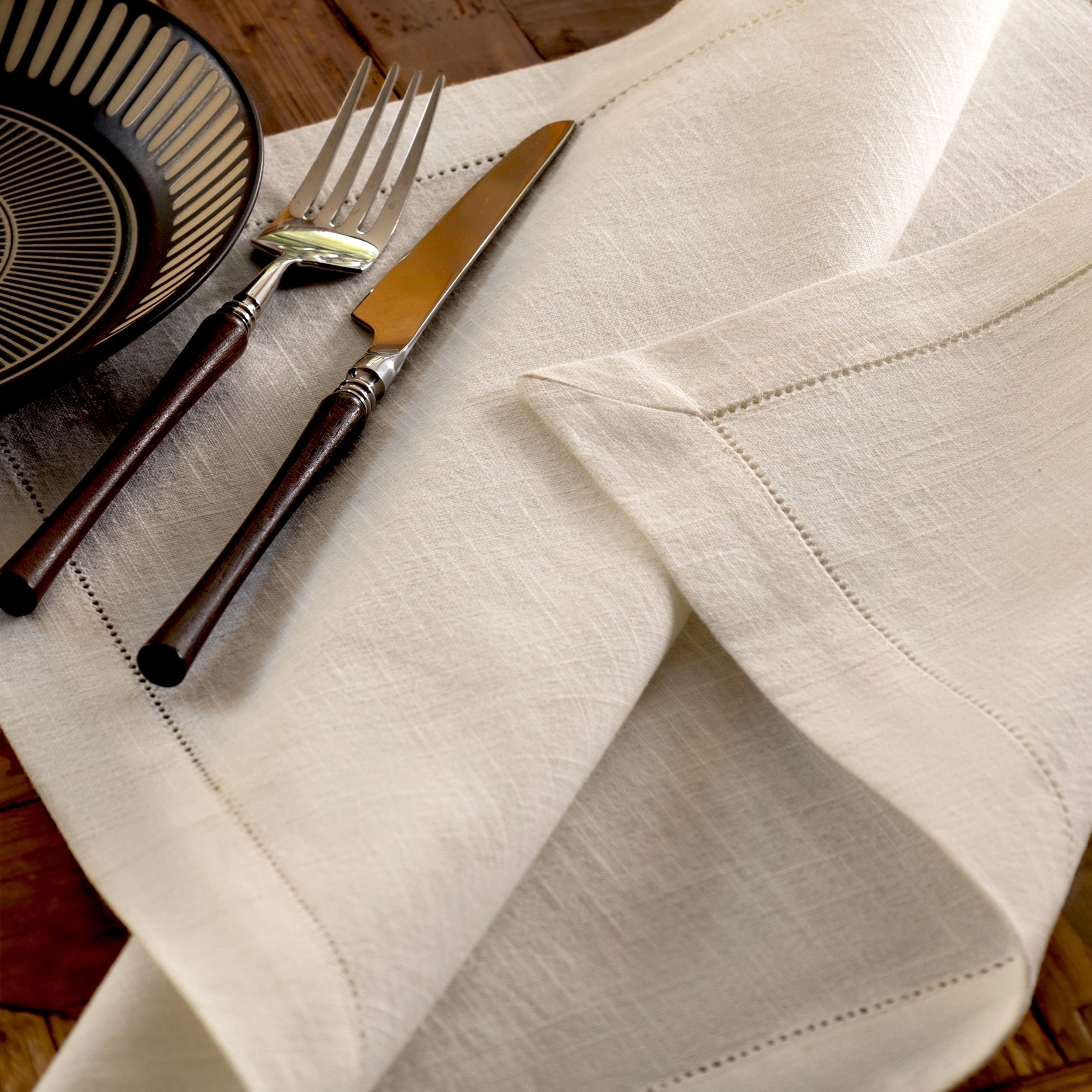 White ramie napkin with hemstitch embroidery detail casually spread on a wooden table