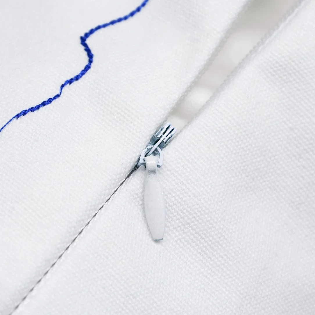 Close-up of the invisible zipper on the white cotton Whimsy throw pillow cover.