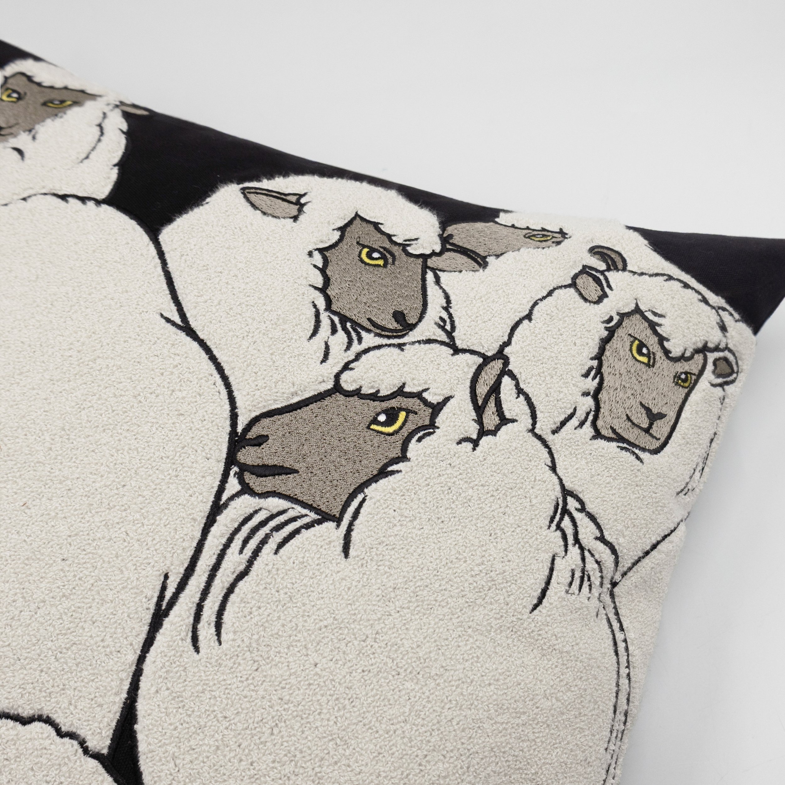 Close-up detail of sheep embroidery on The Flock throw pillow showing textured stitching and chenille embroidery