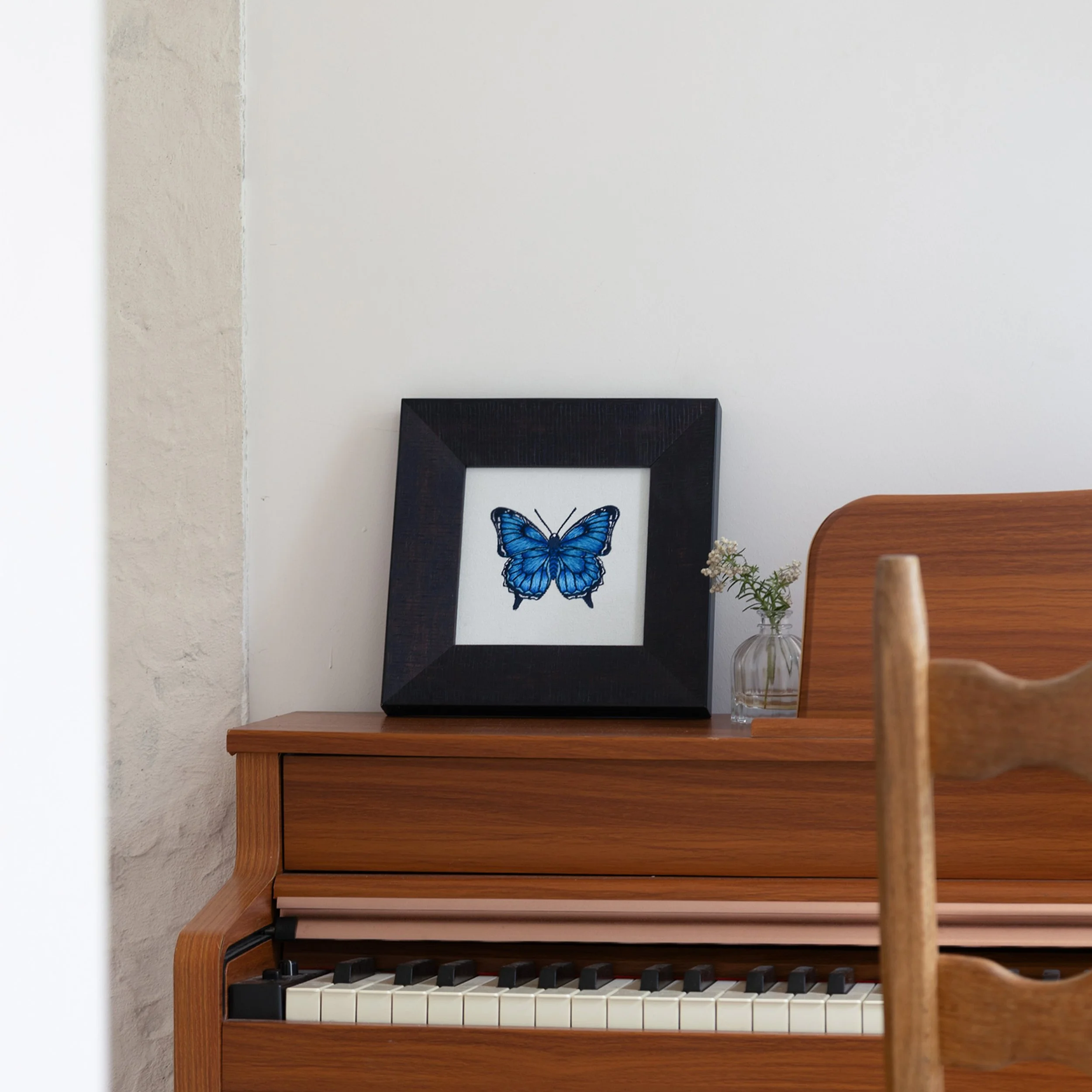 Nocturna butterfly embroidered wall art styled on a wooden piano in a modern interior