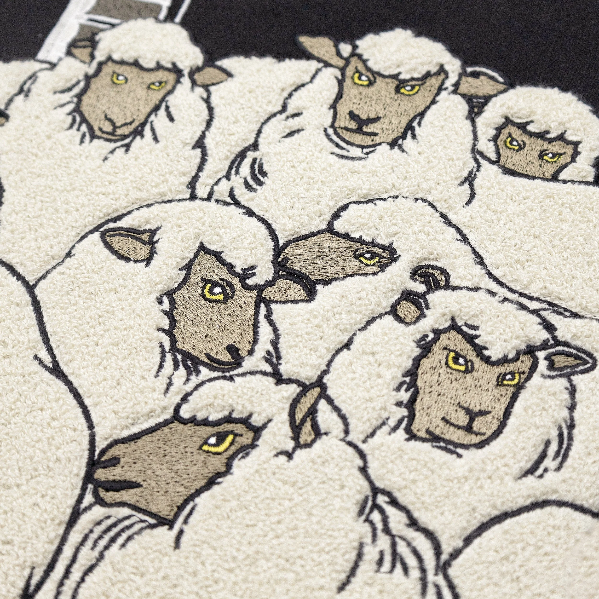 Close-up of chenille sheep embroidery on The Flock wall art showing textured stitching and dimensional details