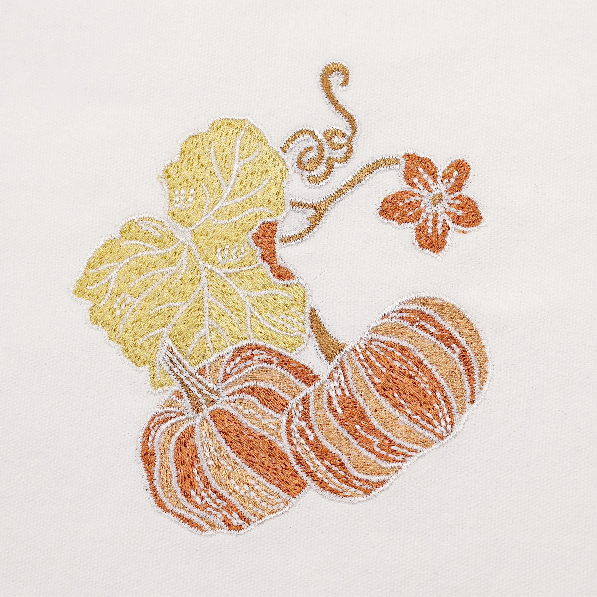 Close-up embroidery detail of pumpkins and leaves — fine stitching on white cotton napkin from Pam Pan, premium fall table linen.