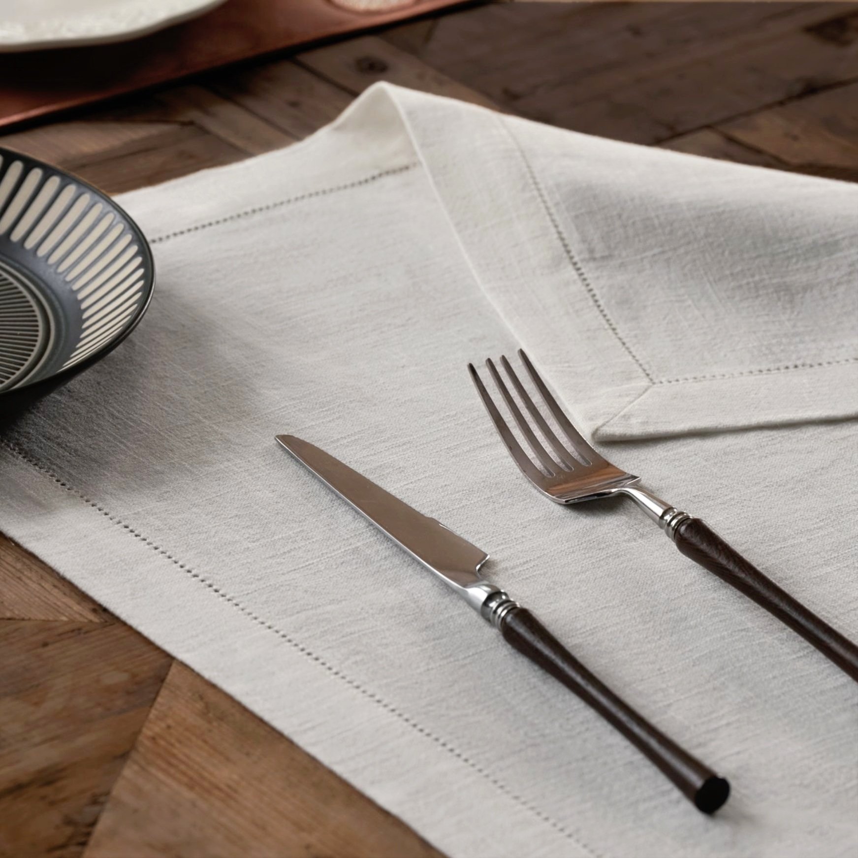 Classic white hemstitched ramie cotton napkin casually spread on a wooden table