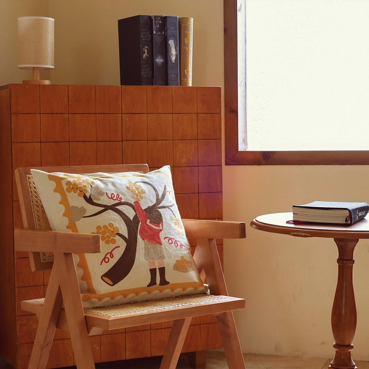 Wild Corner embroidered throw pillow on a wooden chair with warm indoor lighting