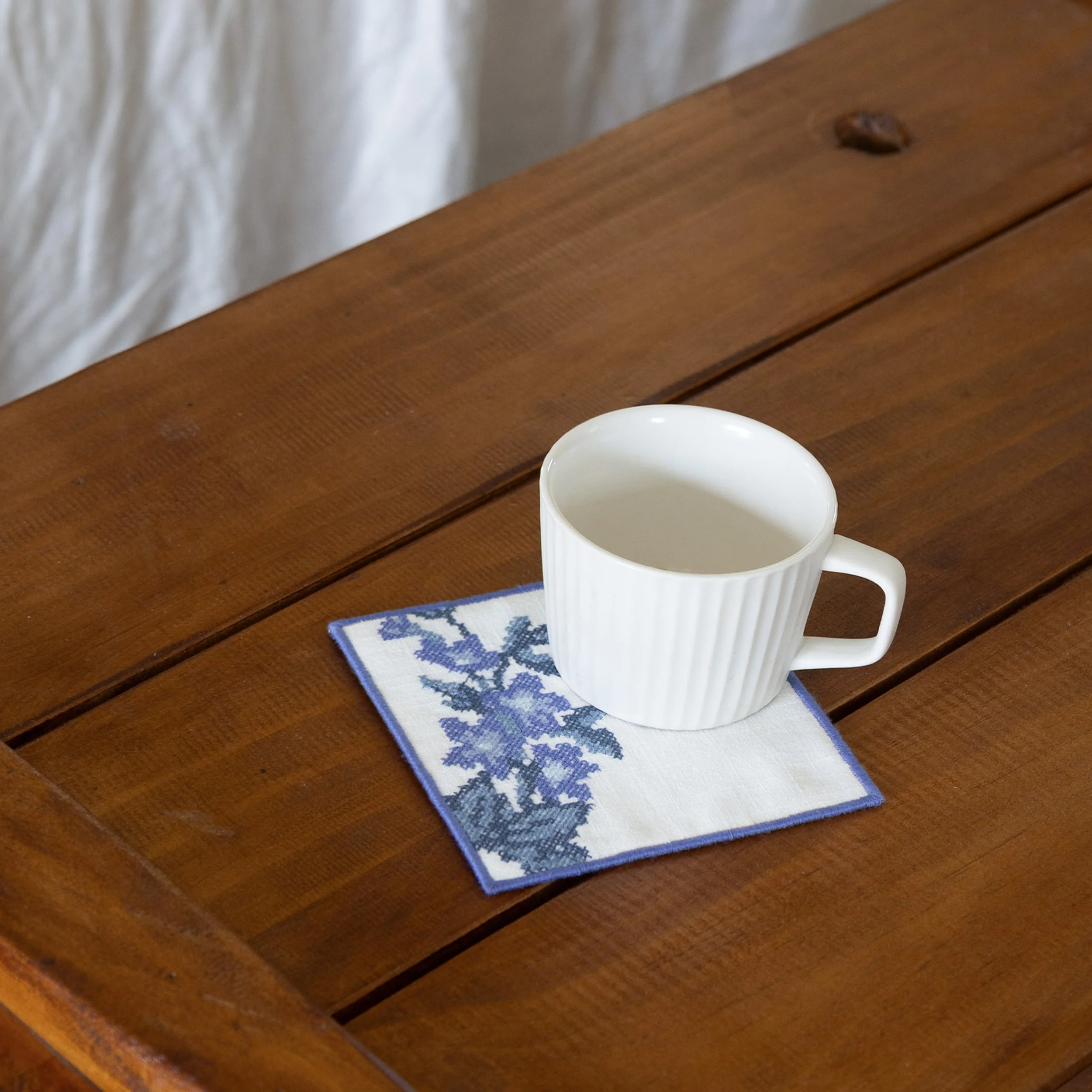Bouquet embroidered floral coaster styled with a white ceramic mug on a wooden table