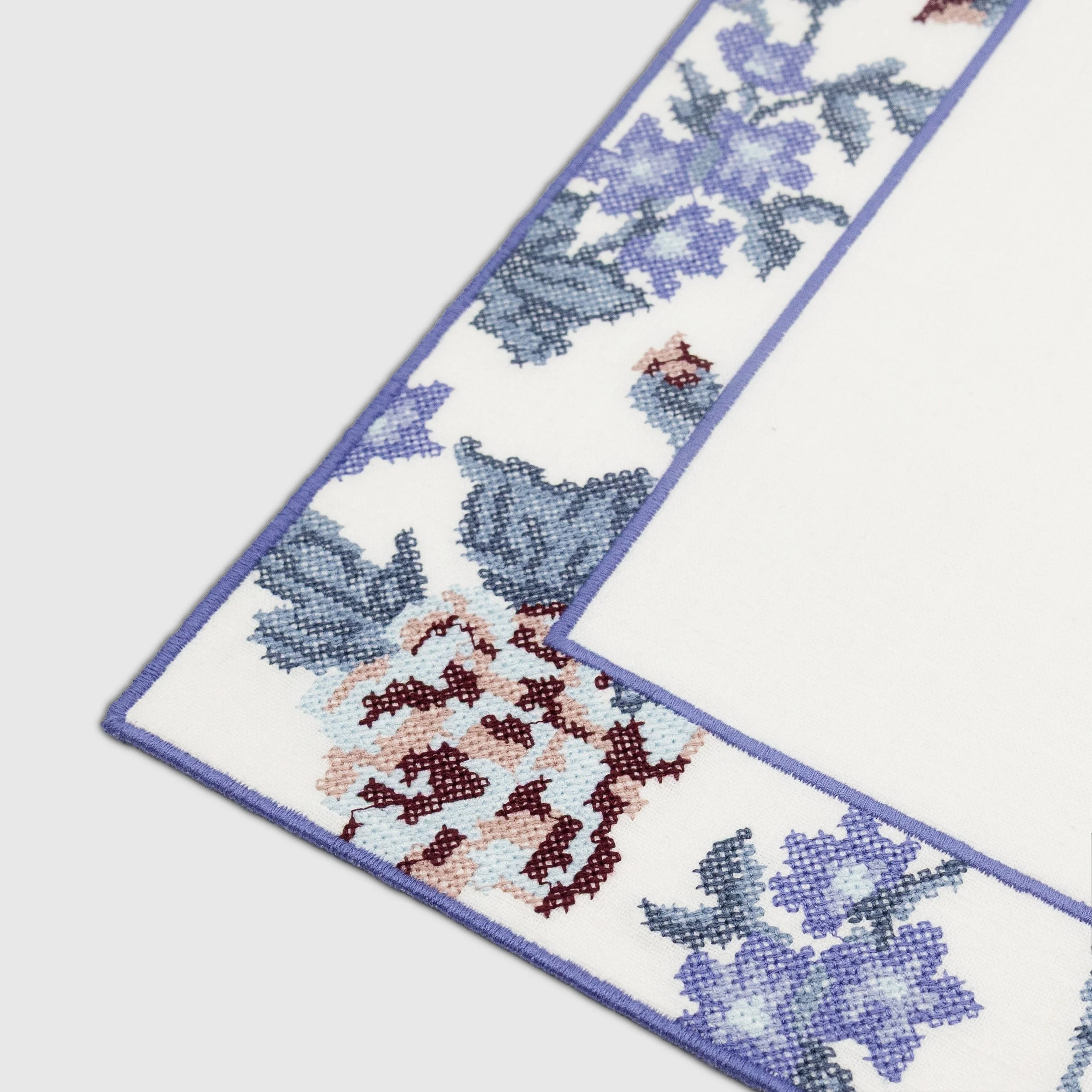 Detailed view of cross-stitch floral embroidery on the corner of the Bouquet placemat