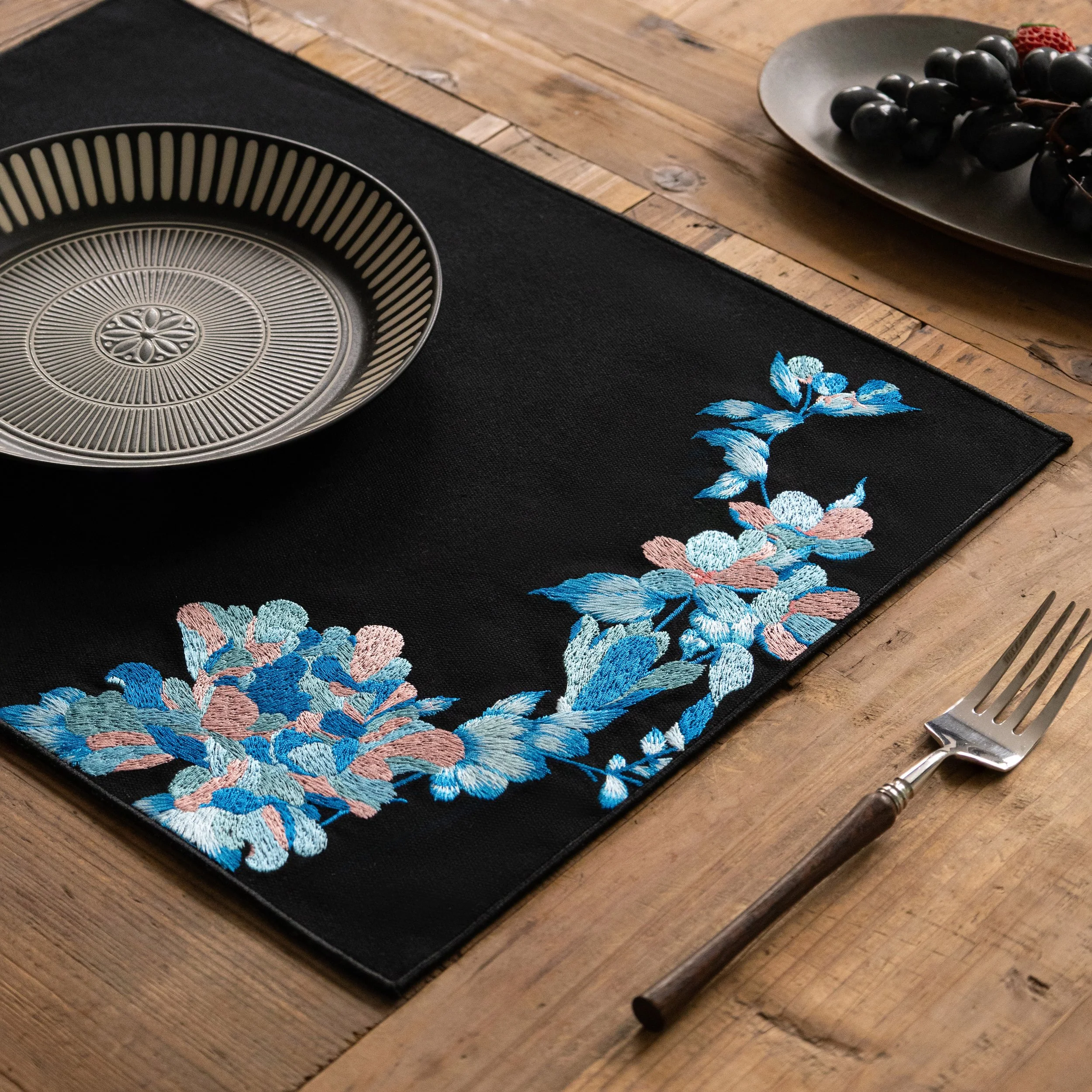 Blue flowers embroidered Etherelle Placemat on a light toned wooden table