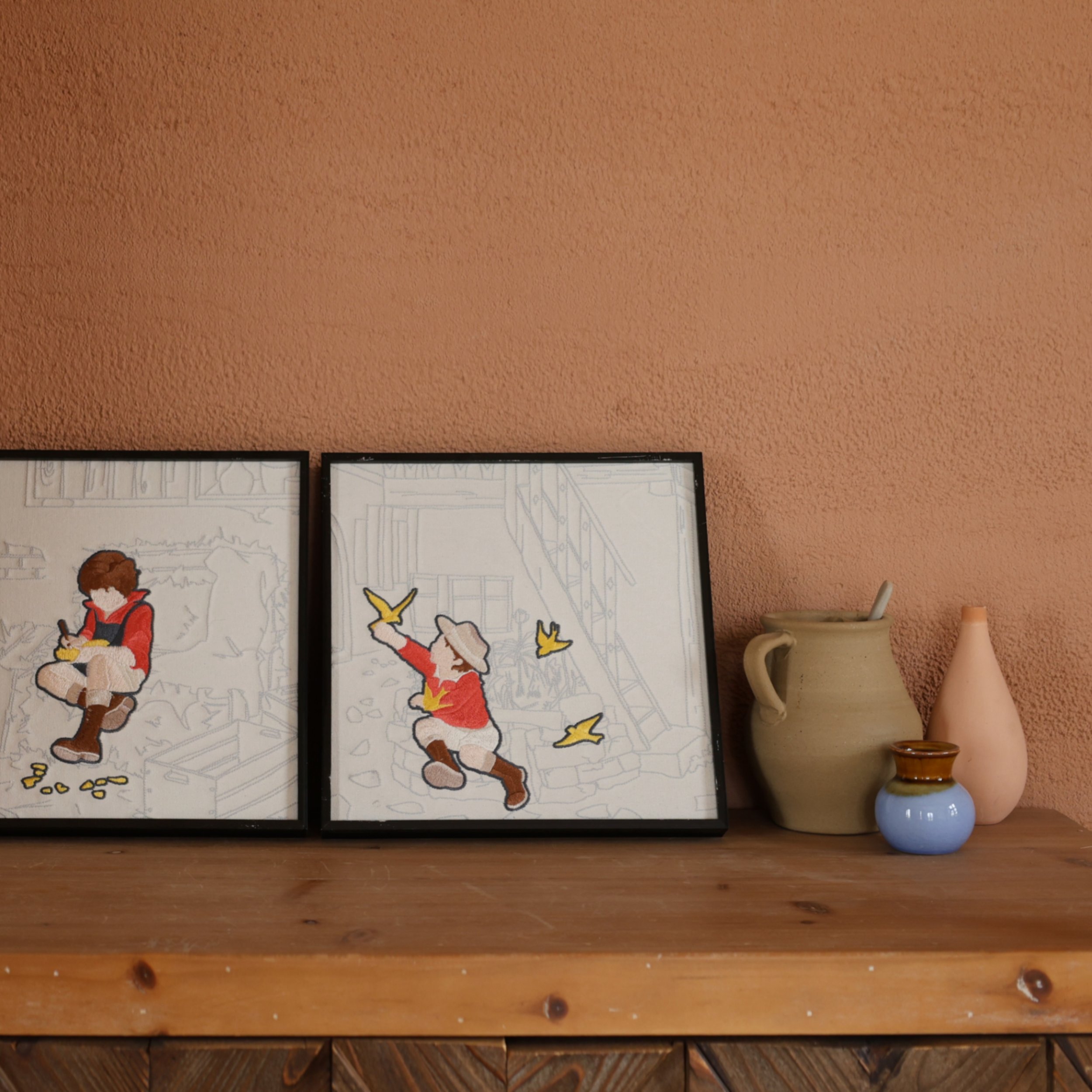 Selected embroidery wall art pieces from Wild Corner set on a counter against a terracotta wall