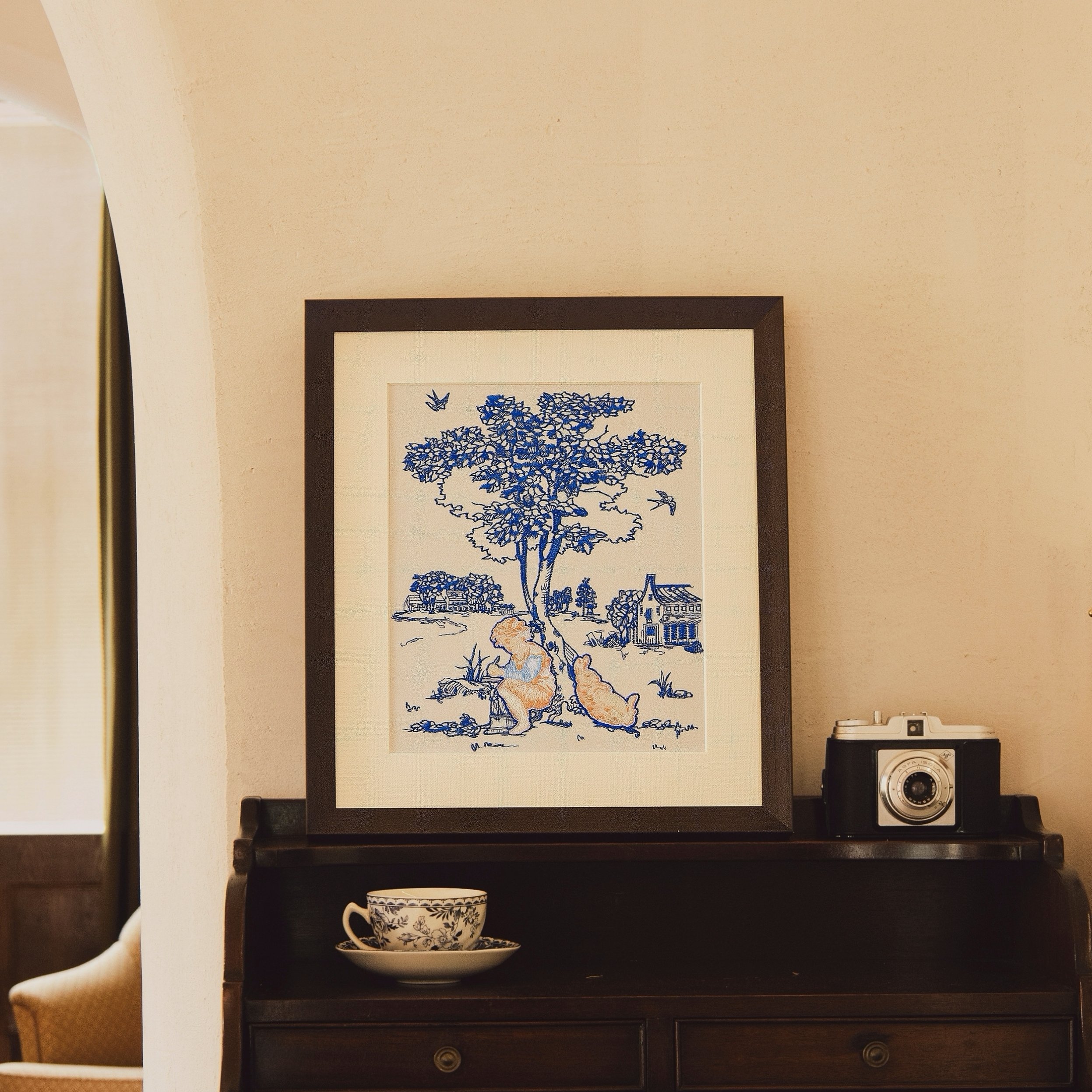Blue Jouy childhood whimsy embroidery art in dark brown frame in a vintage setting