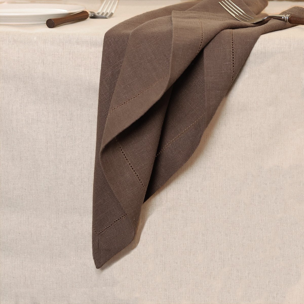 Casual drape of Pam Pan's brown hemstitched napkin made from ramie blend