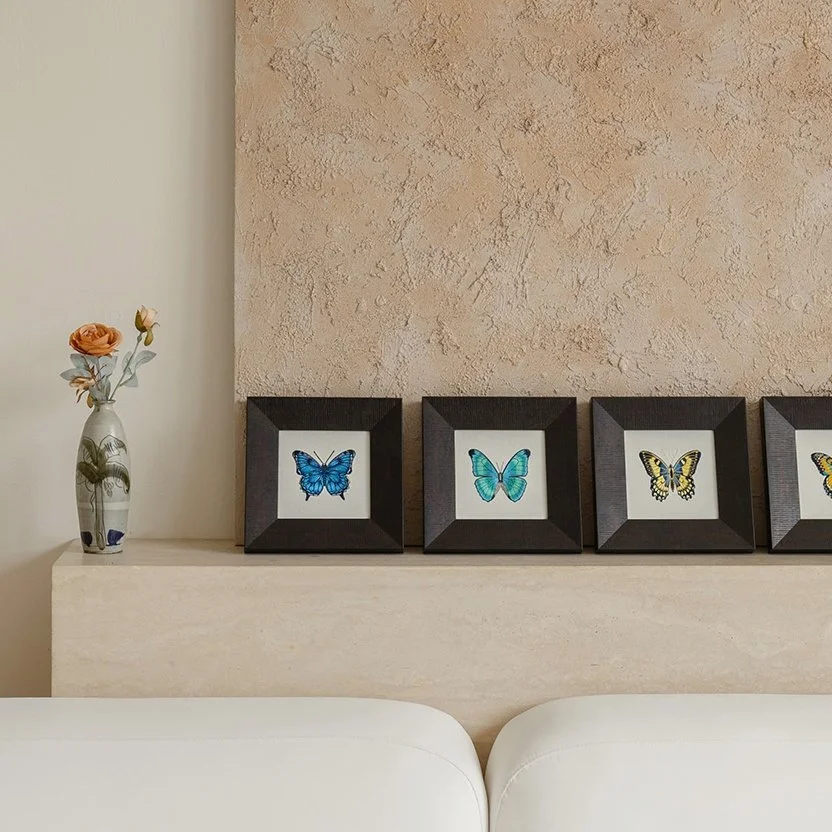 Papilio butterfly embroidery collection displayed on a mantel, featuring four framed embroidered butterfly artworks in complementary color palettes.