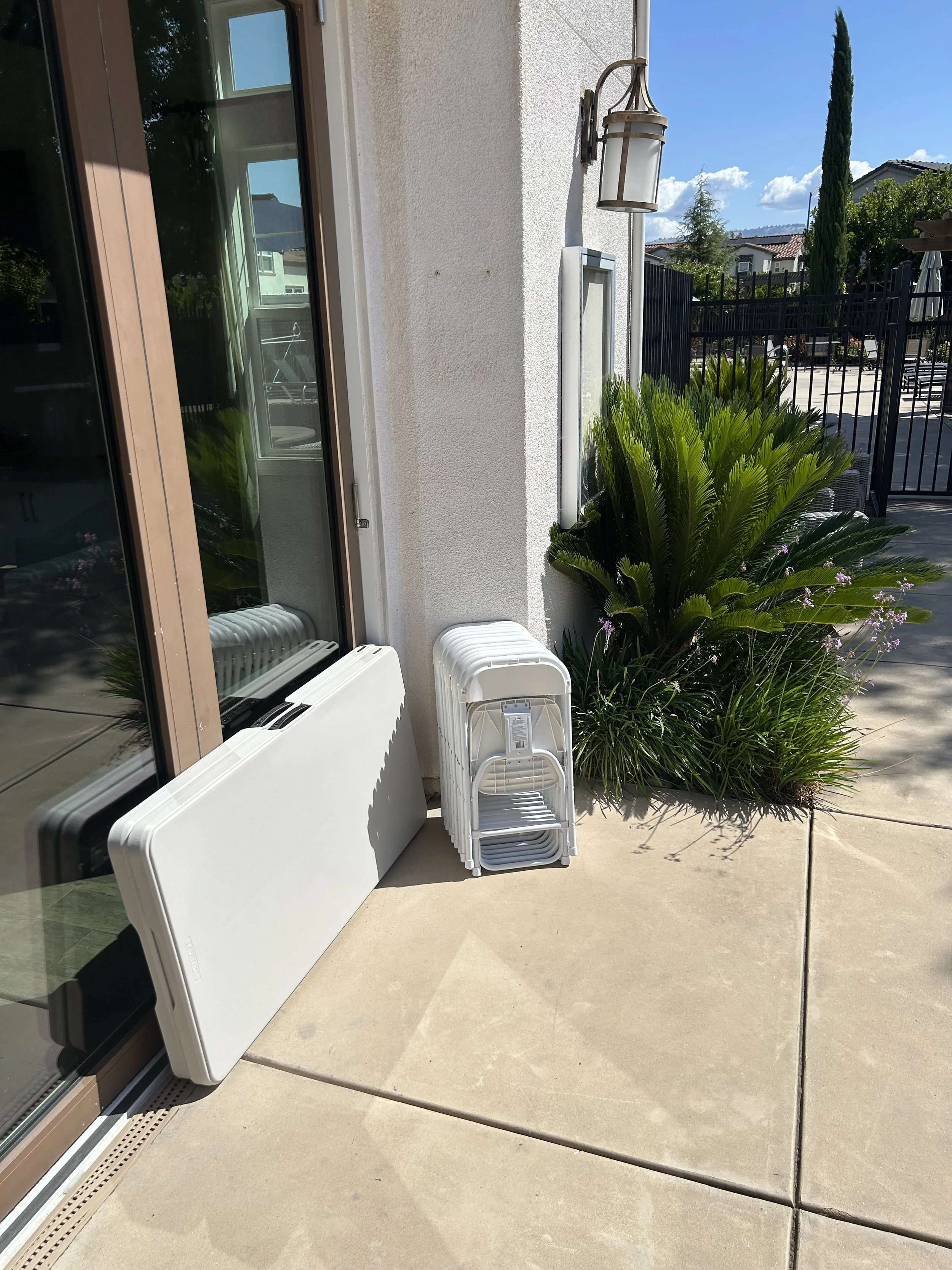 White folding kids chairs and folding tables delivered and stacked at a customer's pool house door