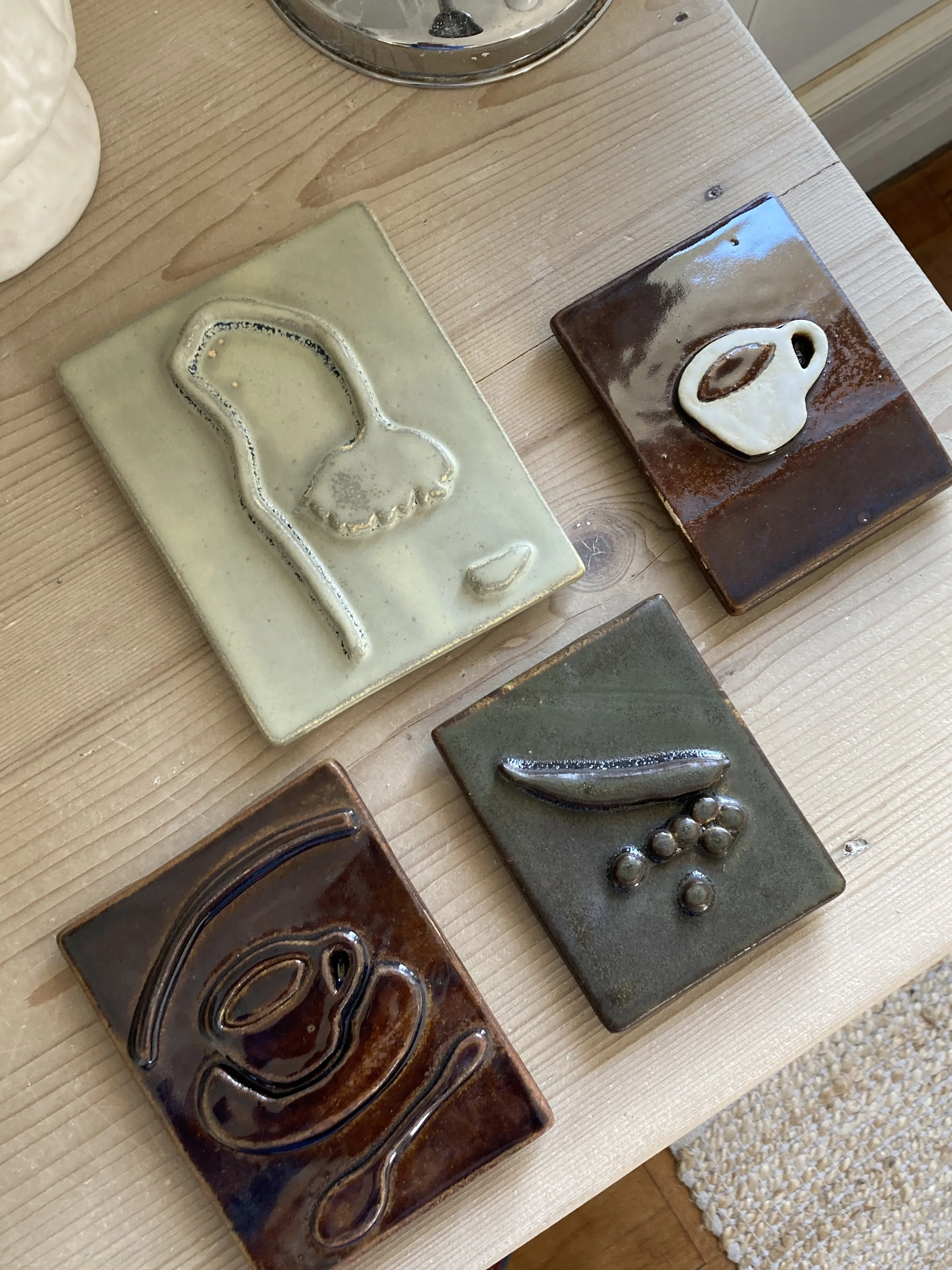 Bas-reliefs en céramique représentant diverses formes telles qu'une une tasse, des petits pois et une fleur.
