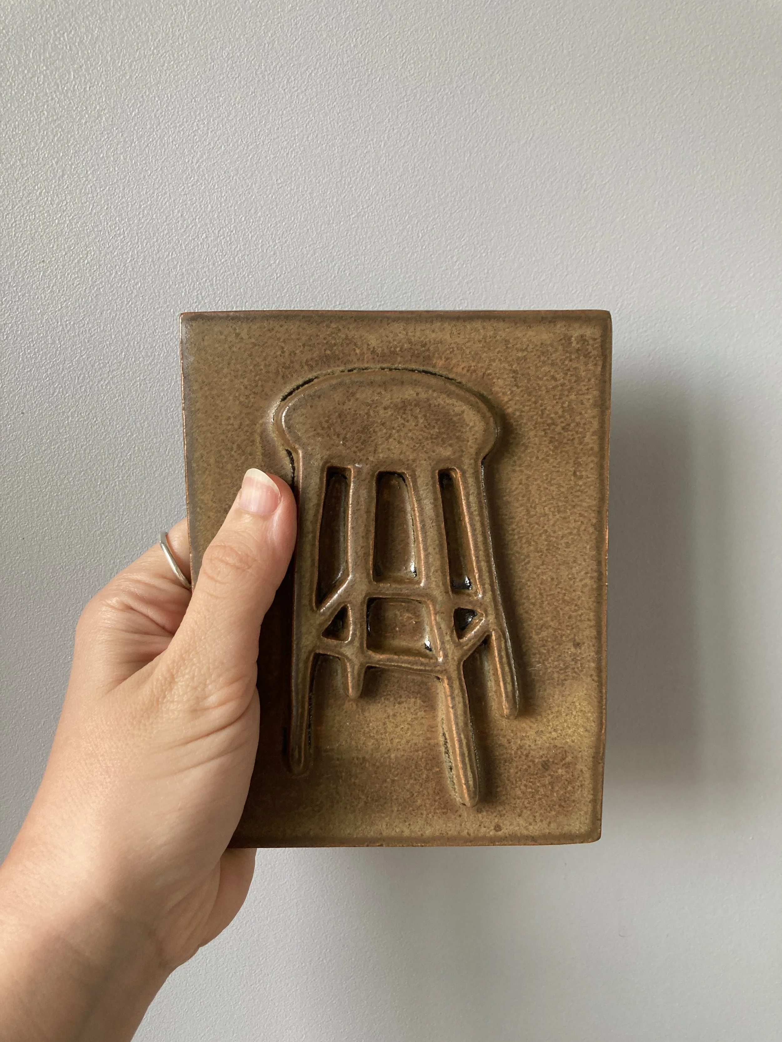 Main dans une main tenant une plaque de cuisson en céramique de couleur marron avec une poignée en forme de fouet.
