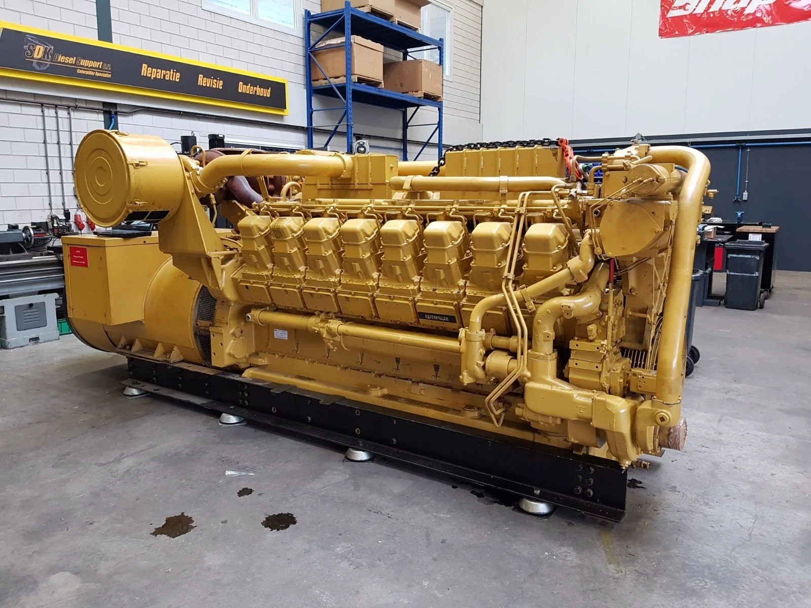 Large industrial Caterpillar diesel engine in a workshop, surrounded by repair equipment and tools.