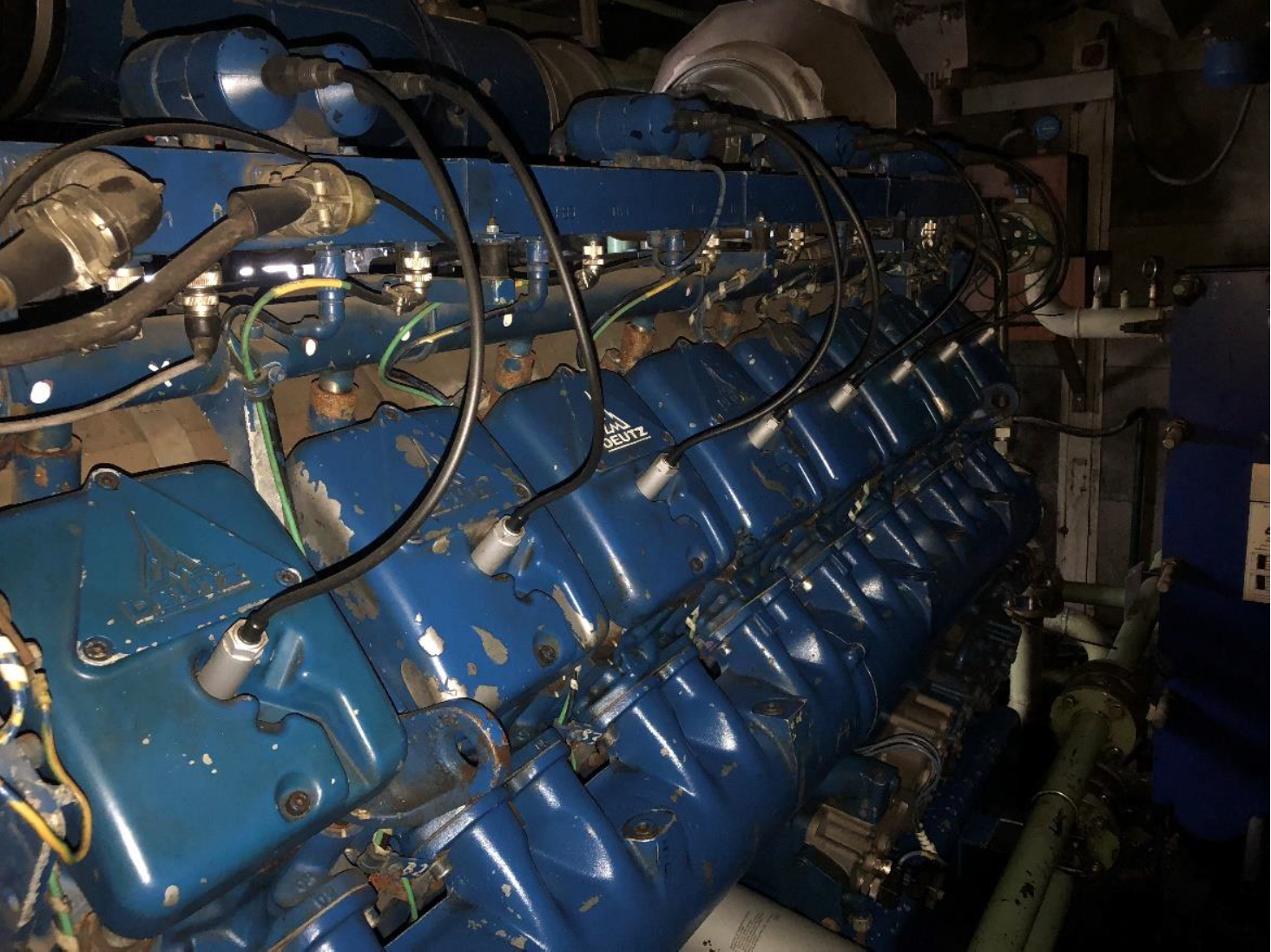 Close-up of a large blue industrial engine with multiple cylinders and wires.
