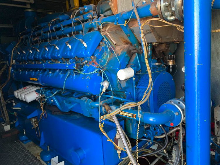 Large industrial blue engine with wires and pipes in a mechanical setting.