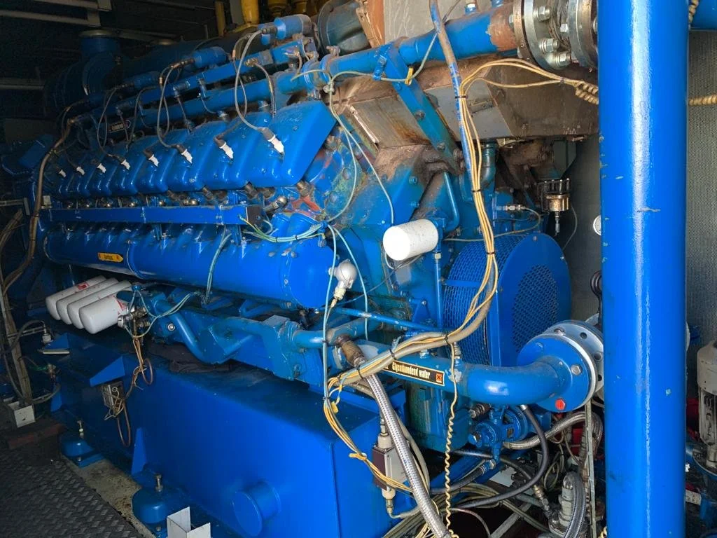 Large industrial blue engine with multiple cylinders and cables.