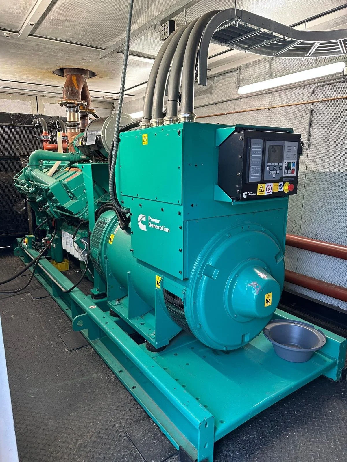Industrial generator in a machinery room with control panel and exhaust pipes, labeled "Power Generation."