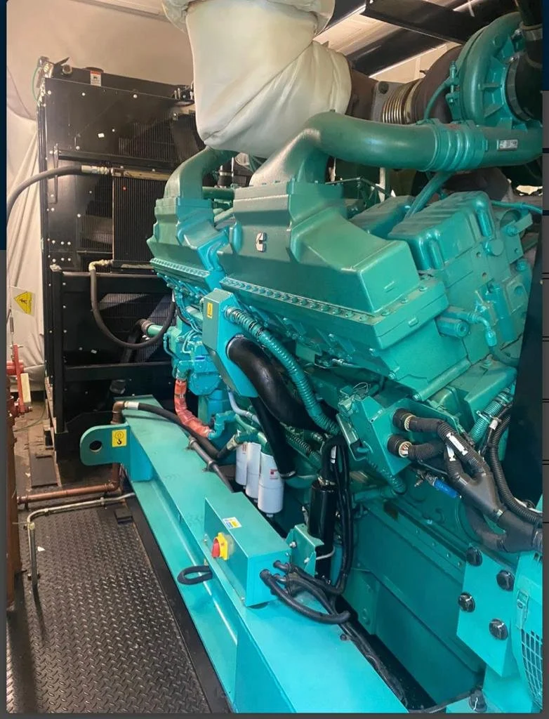 Large green industrial engine with multiple pipes and components inside a facility.