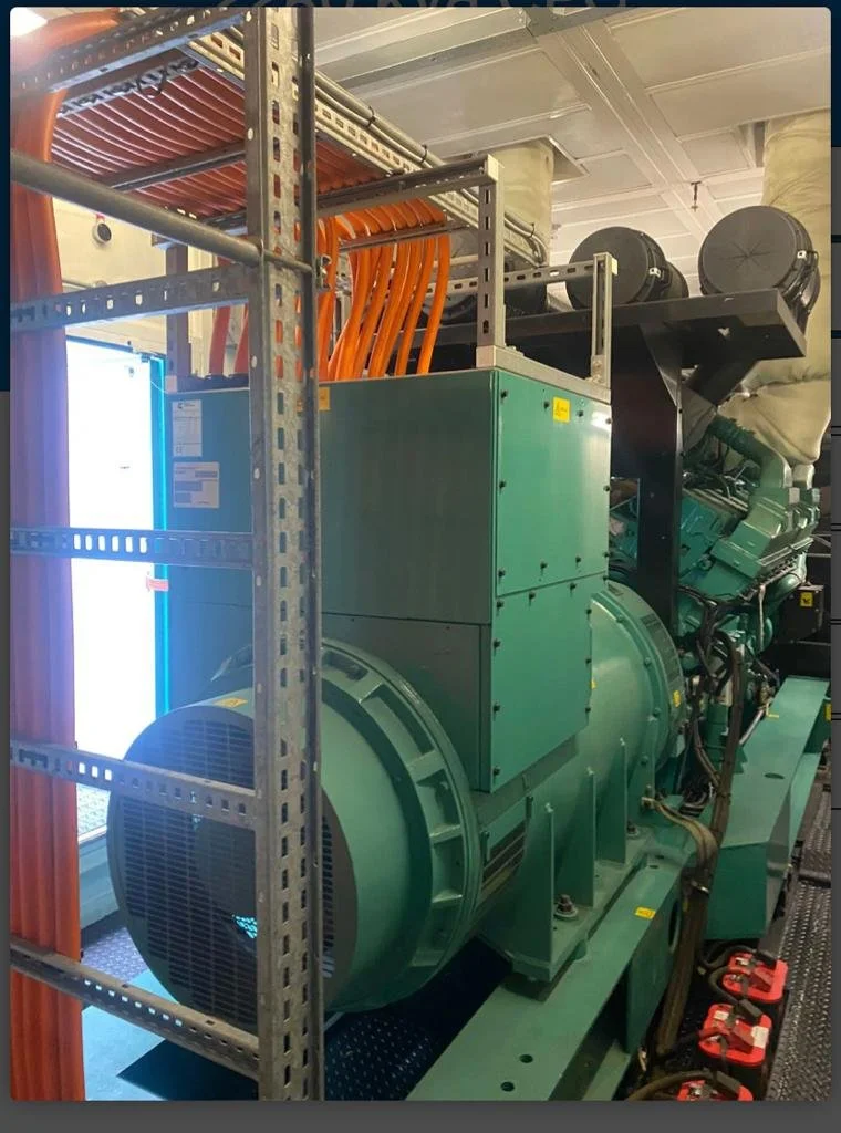 Large industrial generator with green casing and orange cables.