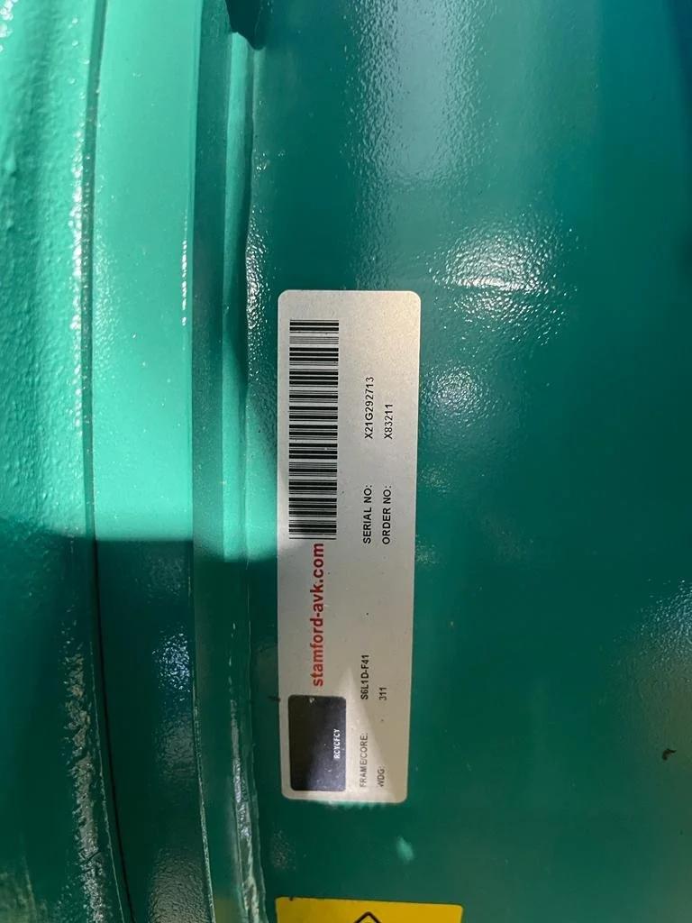 Close-up of a teal-colored industrial machine with a Stamford-AVK label, featuring a barcode and serial number.