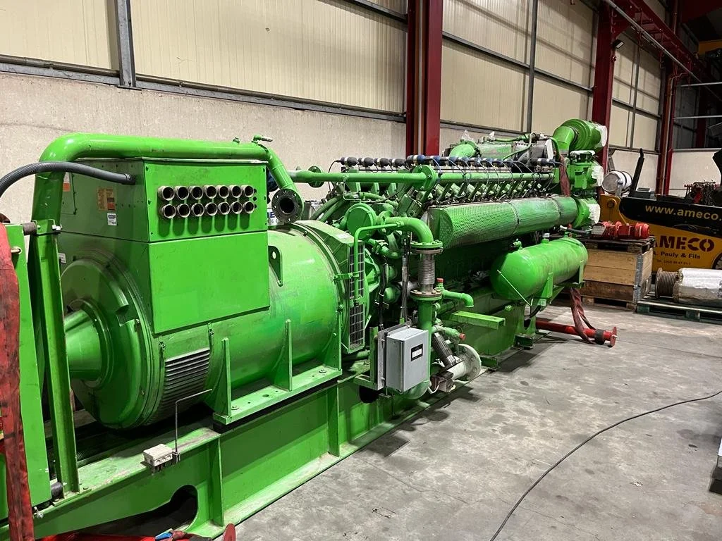 Large green industrial generator or engine in a warehouse setting