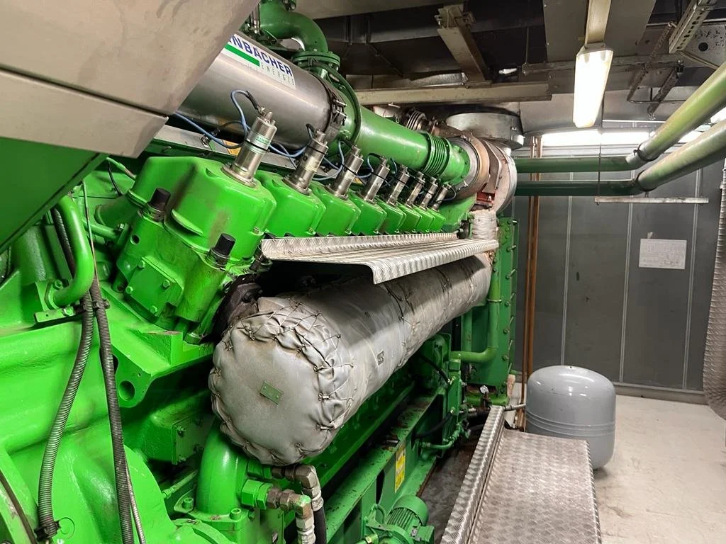 Industrial green engine with piping and mechanical components in a facility.