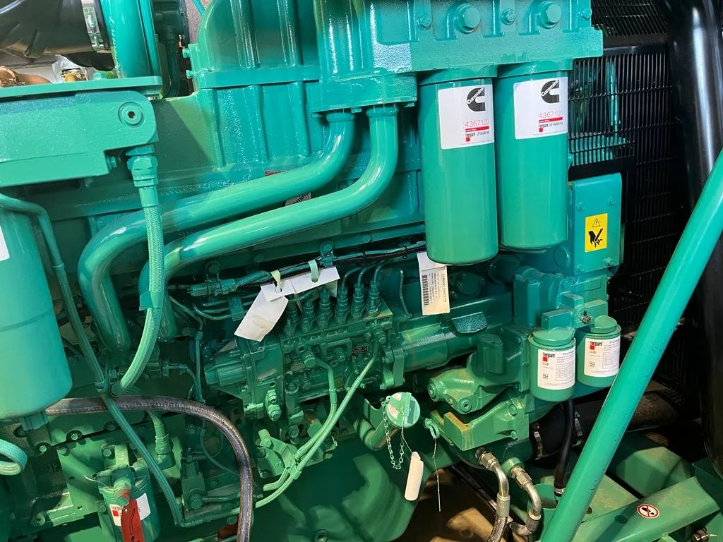 Close-up view of a turbocharged diesel engine with several green components, including pipes, filters, and a Cummins label visible.