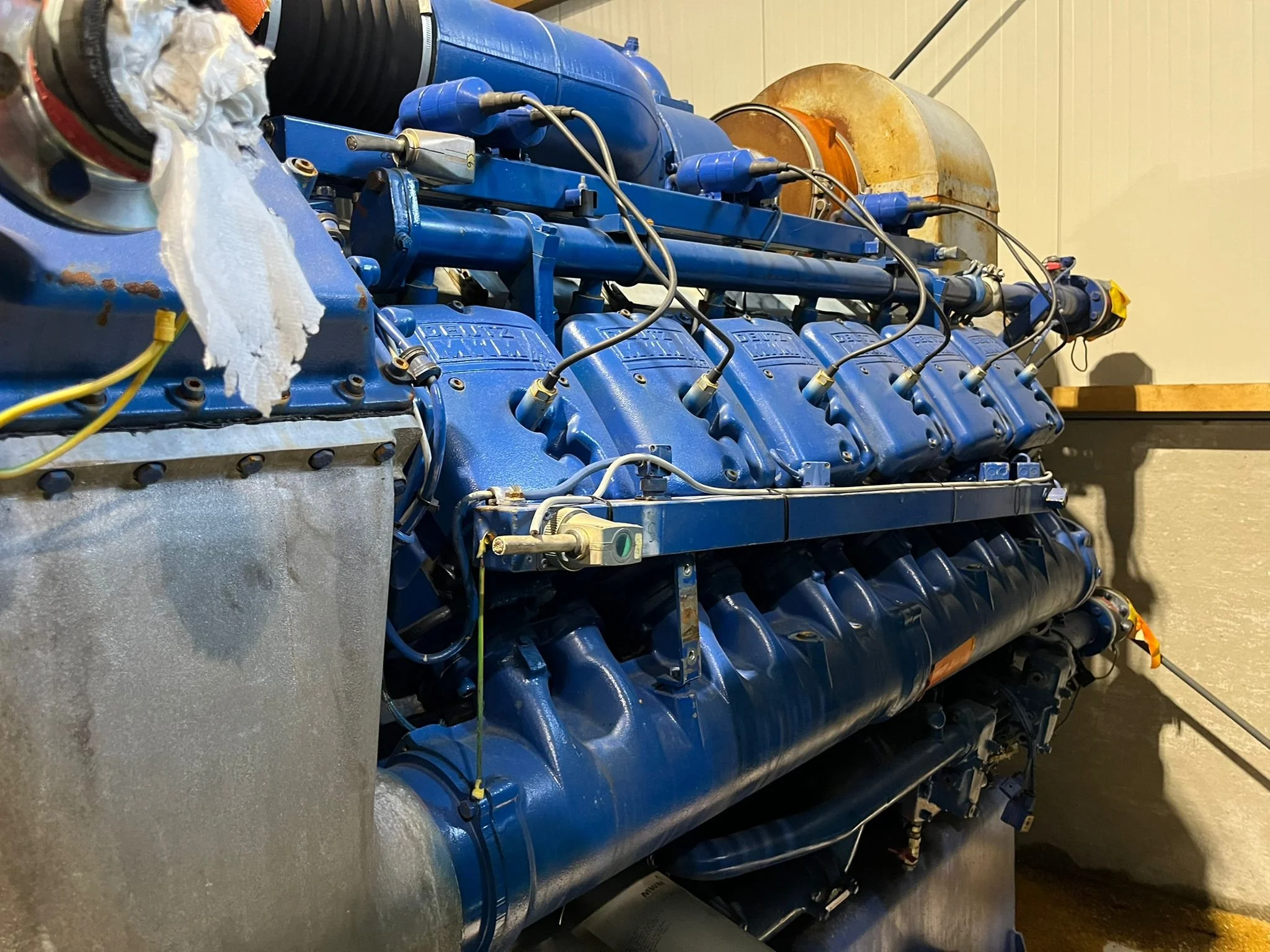 Large industrial diesel engine with blue components and connected wiring in a factory setting.