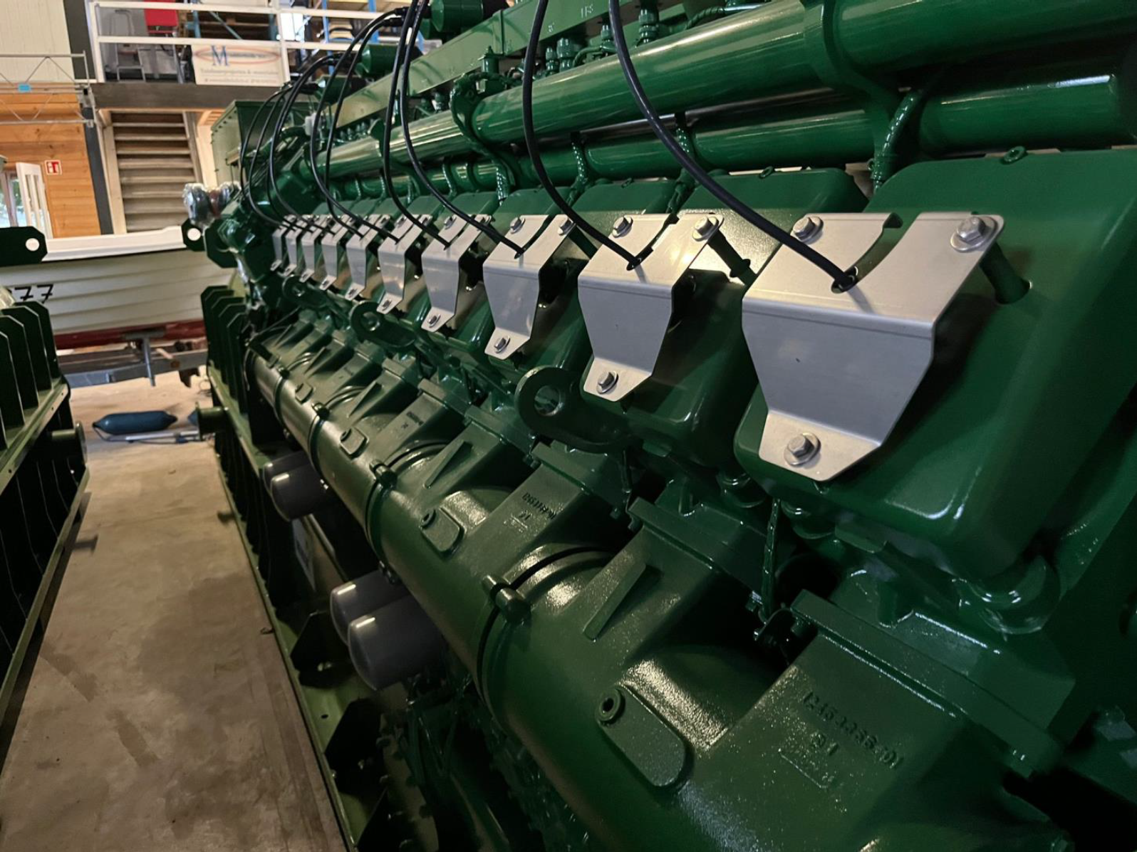 Large green industrial engine with metal components in a workshop.