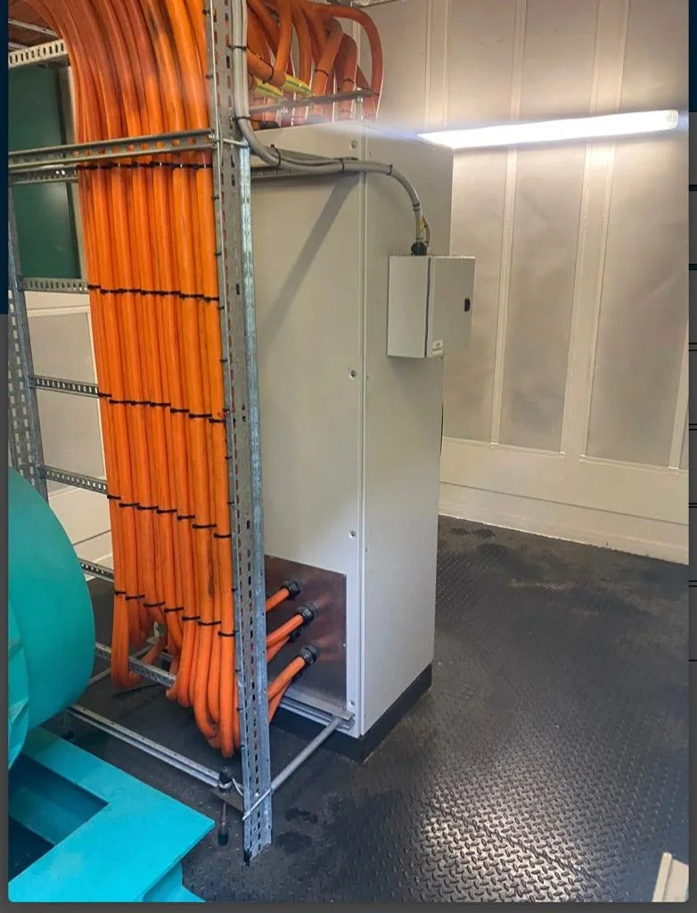 Industrial room with large orange cables connected to electrical equipment.