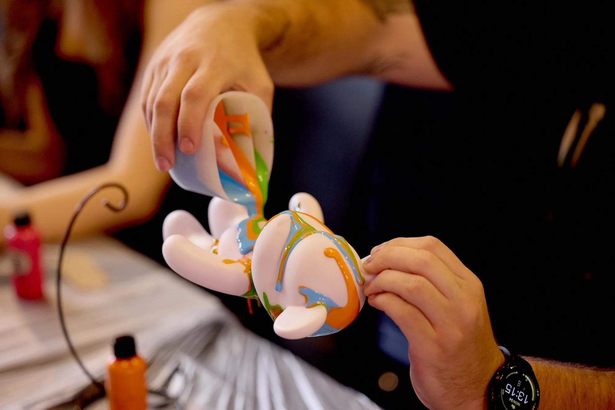 Person painting a ceramic elephant sculpture with colorful glaze.