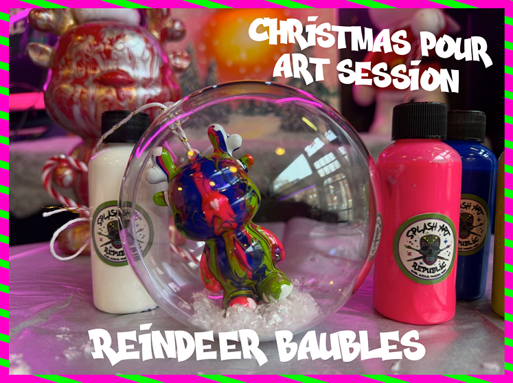 A decorated glass Christmas ornament with a colorful giraffe sculpture inside, surrounded by bottles of paint and holiday decorations for a Christmas art session.