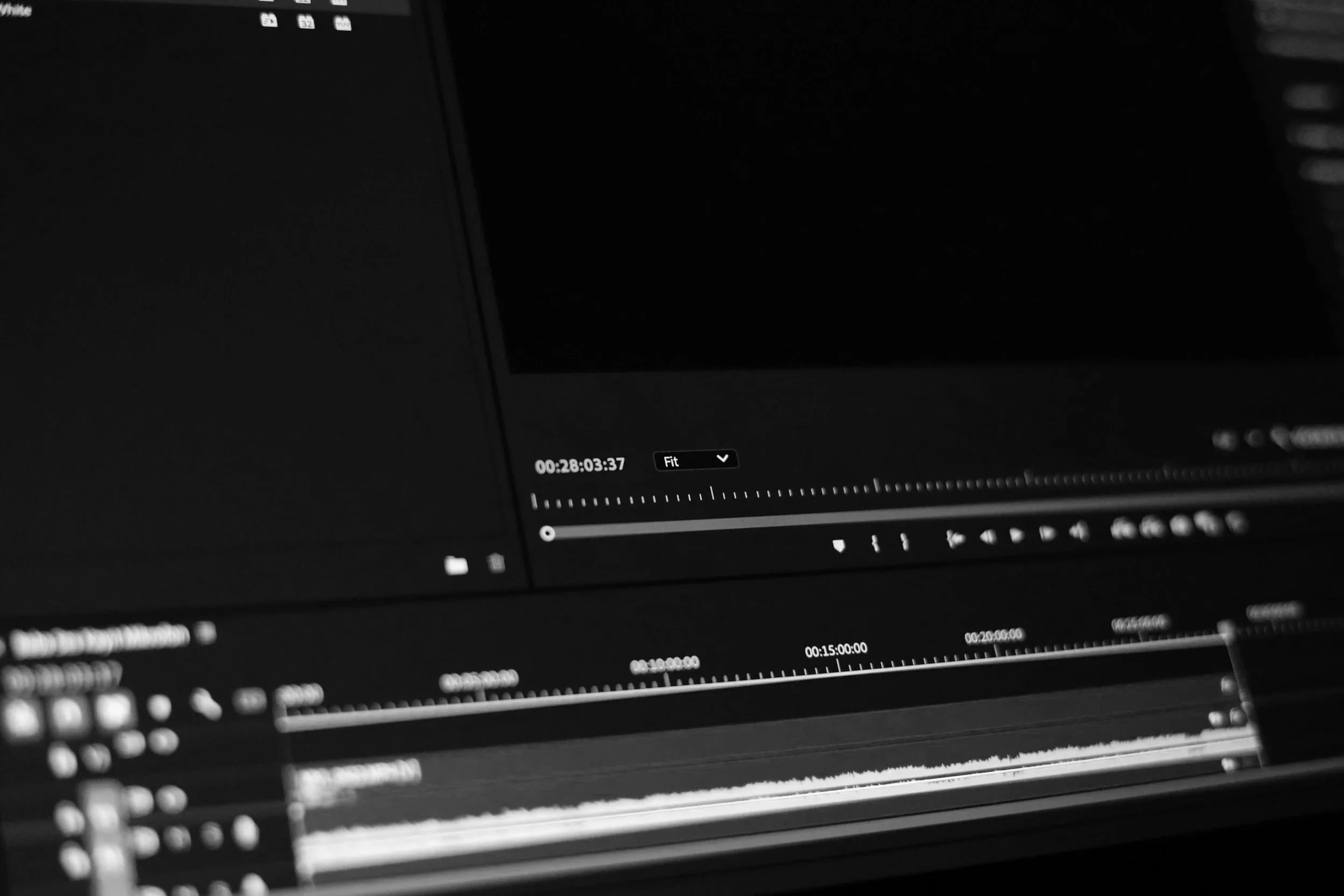 Close-up of a computer screen displaying a video editing software interface with timeline, controls, and black-and-white color scheme.