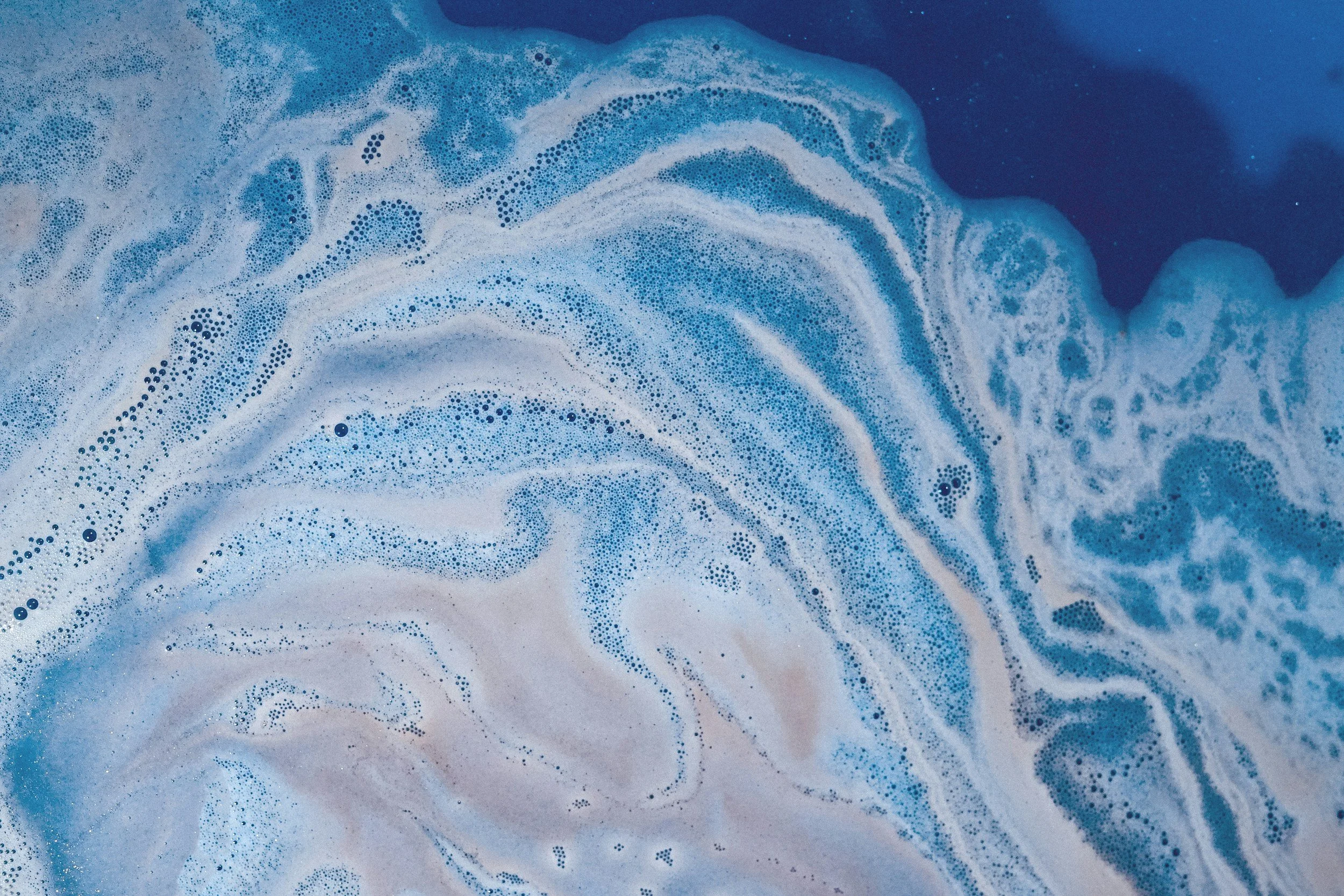 Blue and white swirling foam pattern resembling ocean waves or abstract art.
