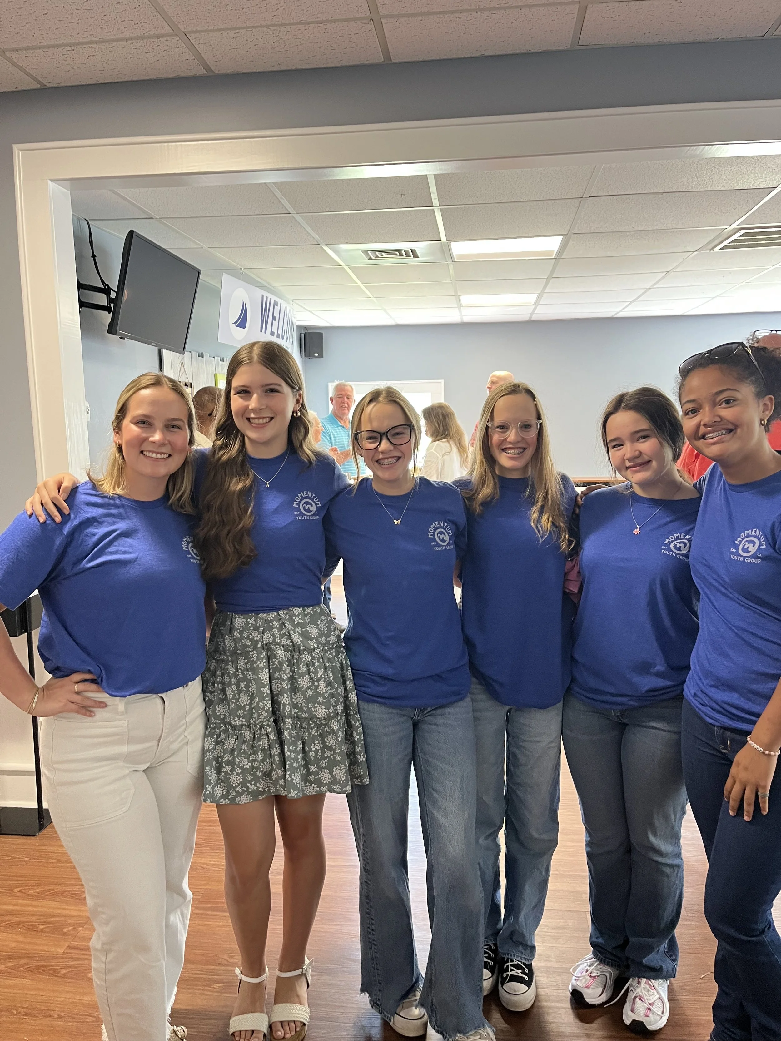 A group of young women in blue tshirts pose and smile