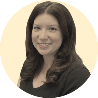 Dana Brown: a woman with long brown hair smiling, wearing a black blazer, against a light beige background.