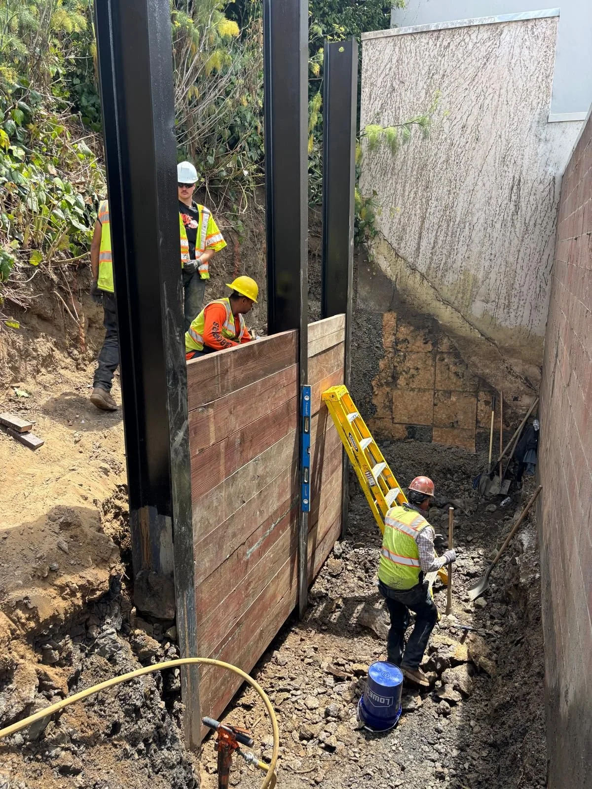 Installation of lagging boards between beams to retain soil.