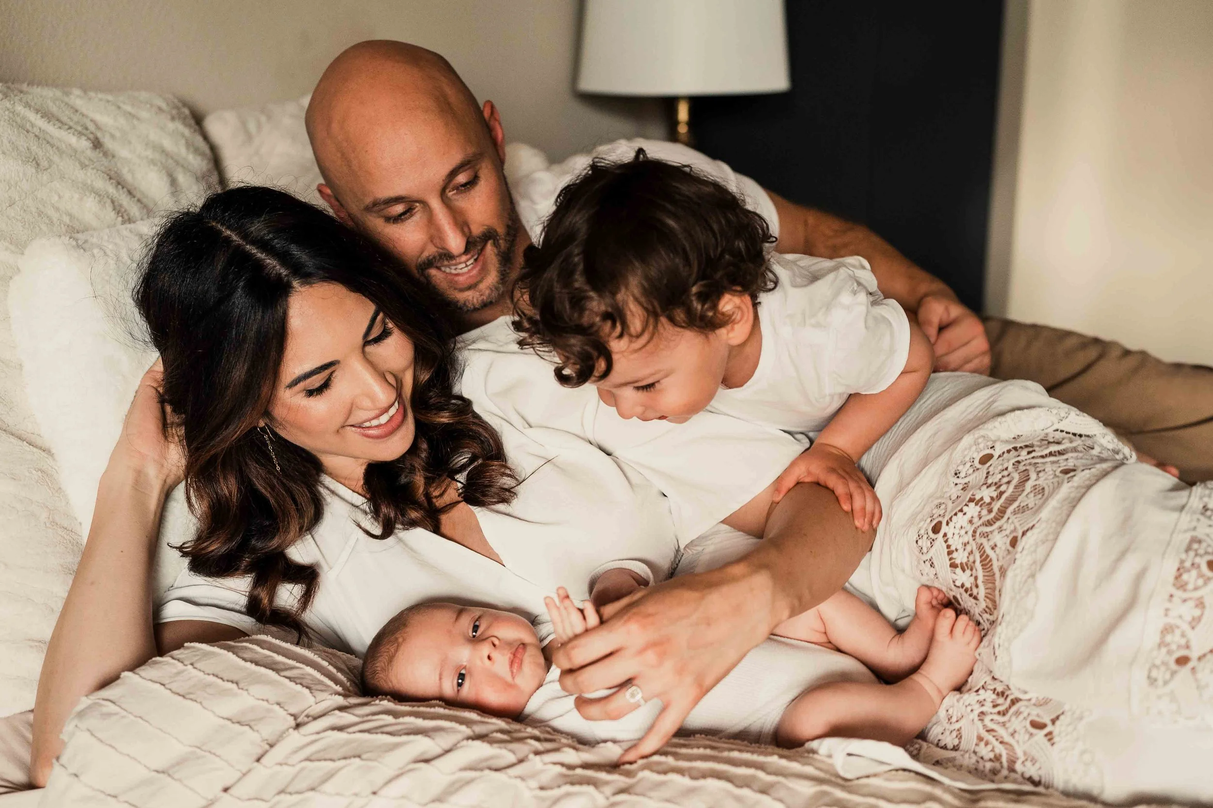 family looking lovingly at newborn on bed