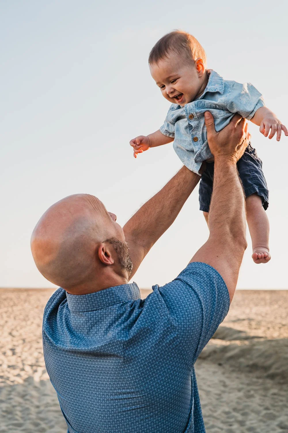 Dad tossing baby up in arms at beach
