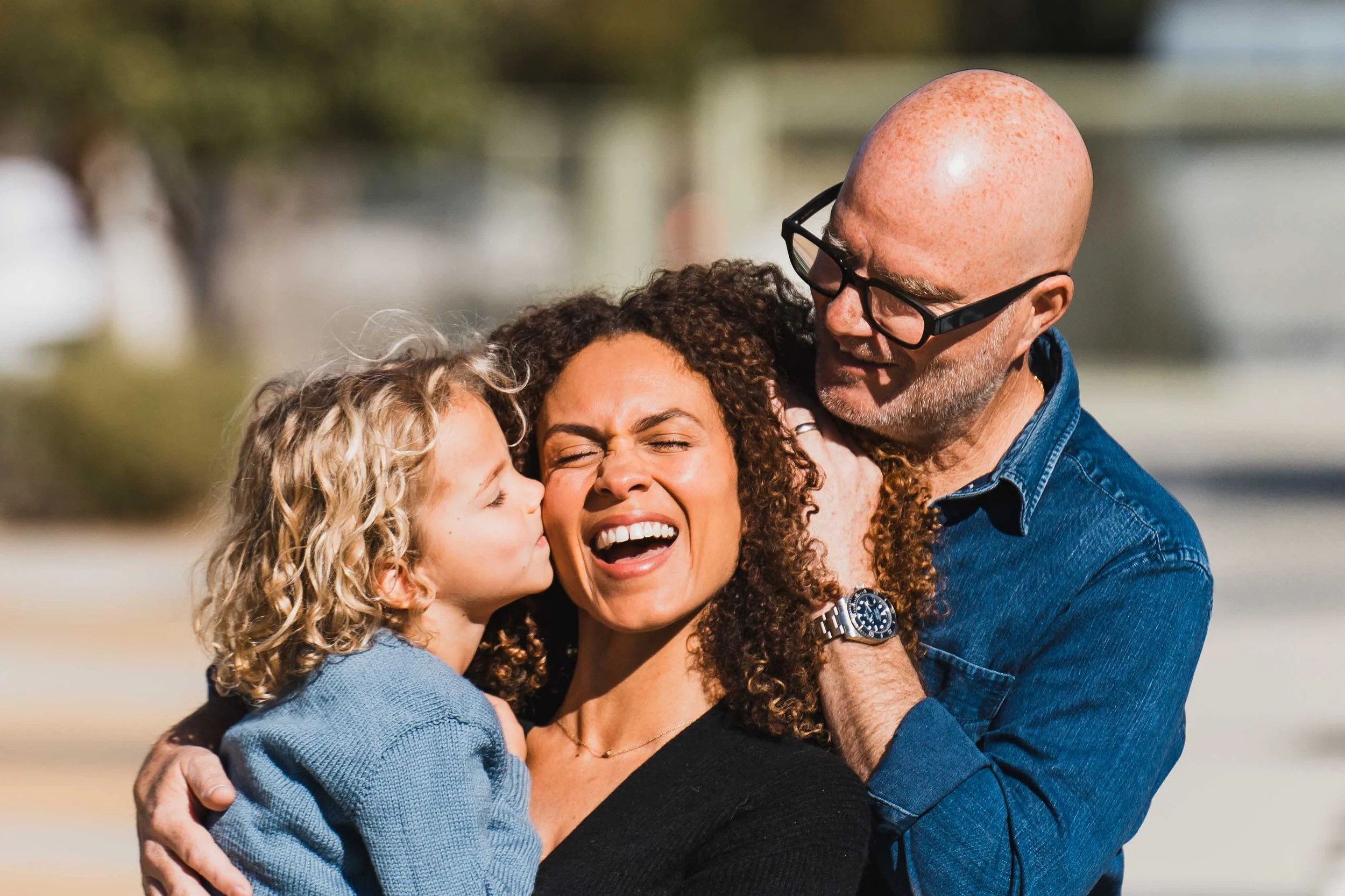 Son kissing mom while dad pulls mom's hair out of her eyes
